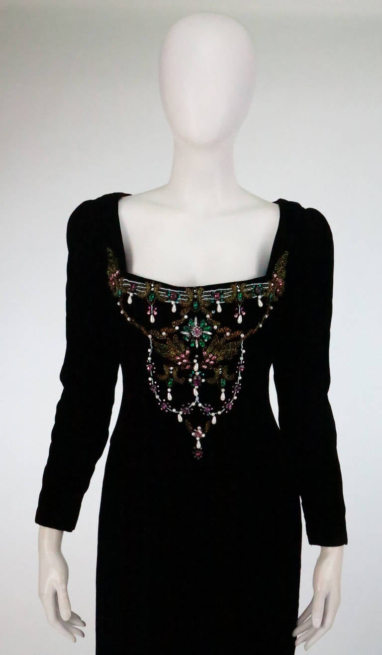 Oscar de la Renta bejeweled black velvet evening gown, dramatic neckline
with jewel set bodice front...Long sleeves, dress is fitted through the waist and hip, slightly gathered skirt sits at hip top, deep back hem vent...Dress is fully lined in