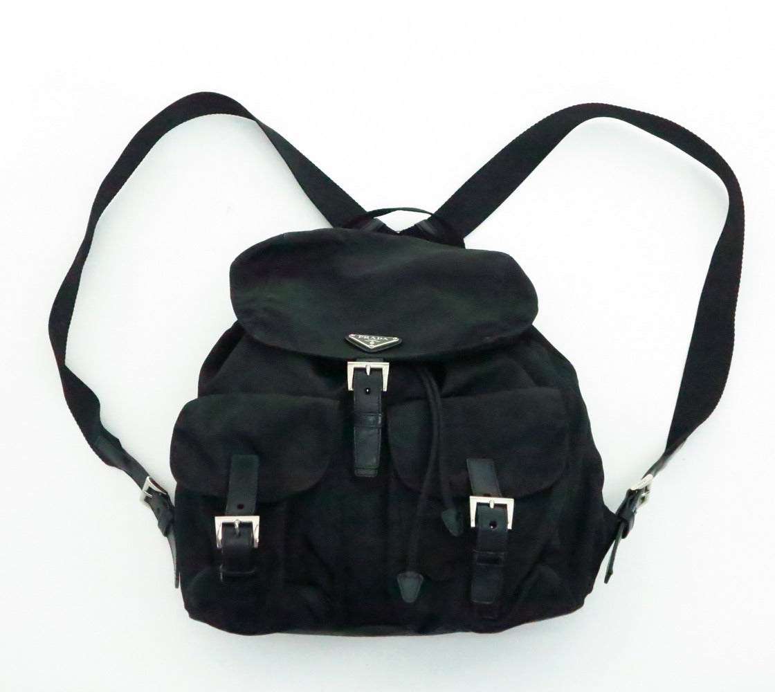 Iconic Prada black nylon & leather back pack…Back pack has nylon web handle at the top back and two adjustable nylon web straps that have adjustable leather straps with silver metal  buckles…At the bag lower front are two flap leather strap, silver