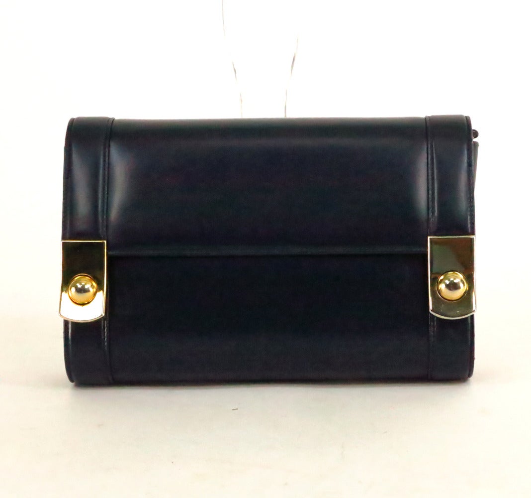 Chic Gucci navy blue box calf clutch bag can be carried as a shoulder bag (with removable gold metal & leather shoulder strap)…The bag has a curved shape, with a flap front, closes with two gold metal button center snaps…The interior is navy blue