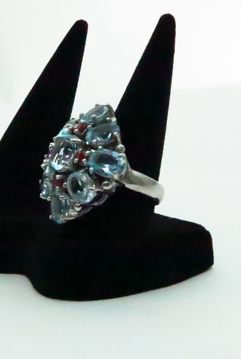 Faux aquamarine & ruby ring set in sterling silver…Nine oval cut faux aquamarine stones with four brilliant cut faux rubies, all stones are prong set with open backs…Marked 925…In excellent condition…

Measurements are:
1 ¼” wide
1 ¼” high