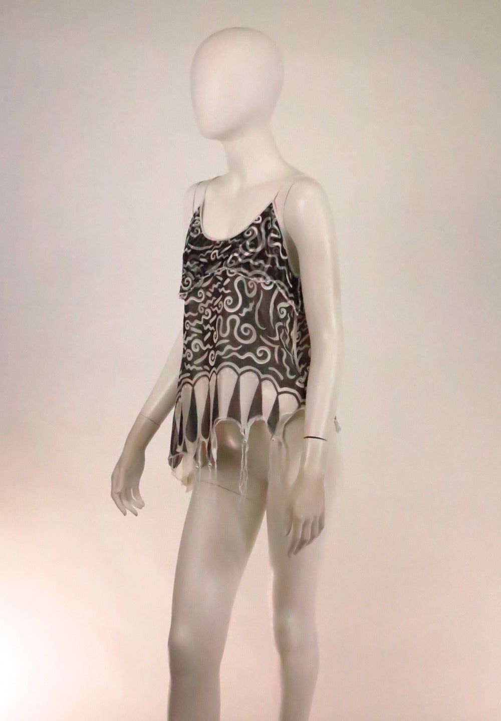 Black and white print top with asymmetrical hem printed with a fringe design...The irregular hem has white fringe...The top is layered silk organdy over white silk charmeuse...Narrow shoulder straps...Closes at the side with a zipper...Fits like a