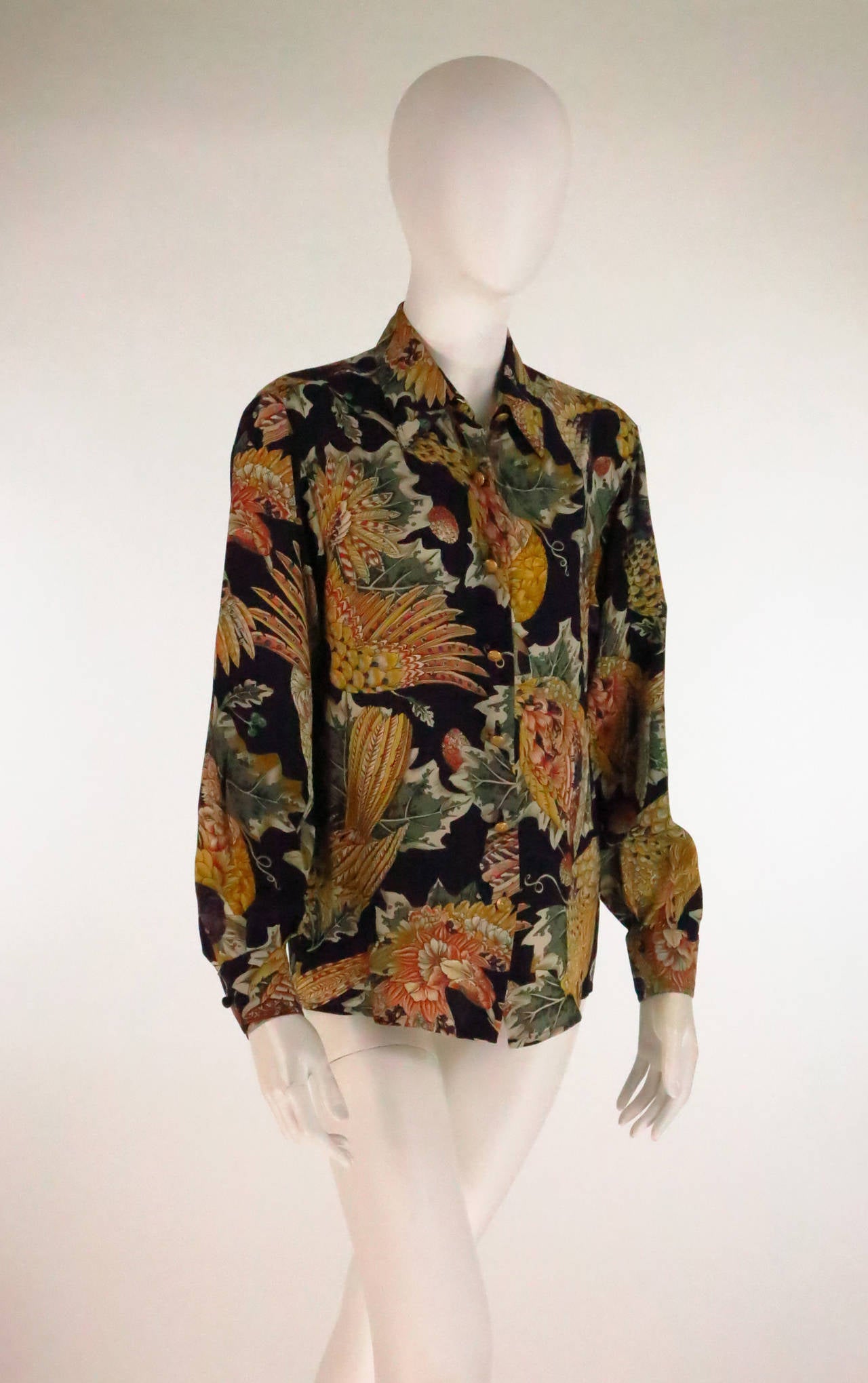 Gorgeous Ferragamo birds of paradise silk print blouse...This was a signature print for Ferragamo and with the black background, this version is a standout...
Long sleeve blouse closes at the front with matte gold logo buttons, straight hem