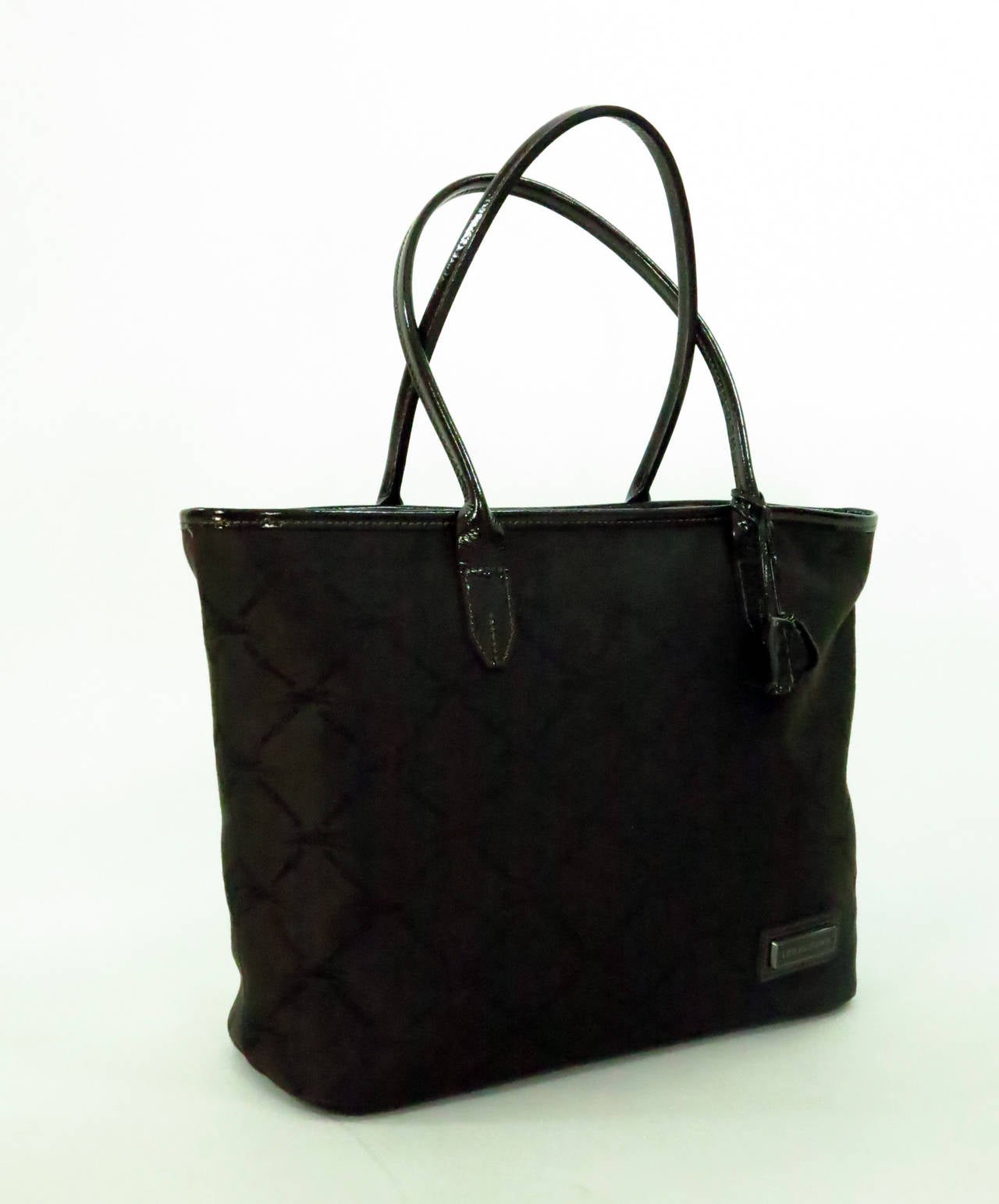 Longchamp double handle tote bag in chocolate brown patent leather & logo fabric...Zipper top closure, attached patent leather flower charm...The interior is fully lined and  has a single zipper compartment & a strap for keys...This was purchased in