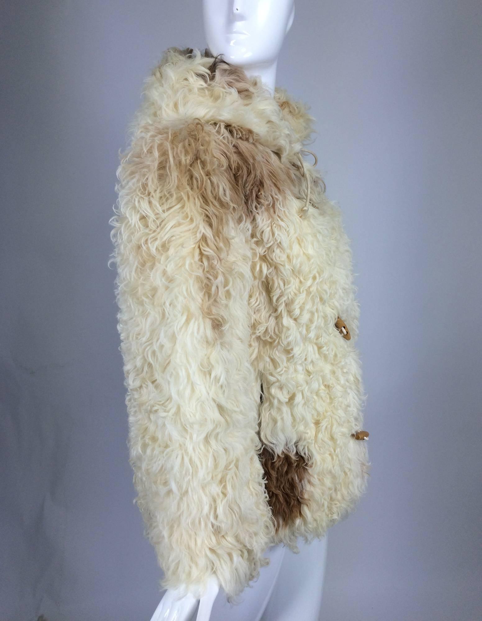 Mongolian lamb cream & tan hooded toggle parka jacket 1960s...Shaggy, cream & tan fur hooded jacket...Long sleeves, front pockets, attached hood with draw cord closure at the neck front...Closes with cord & wooden toggles at the front...The coat is