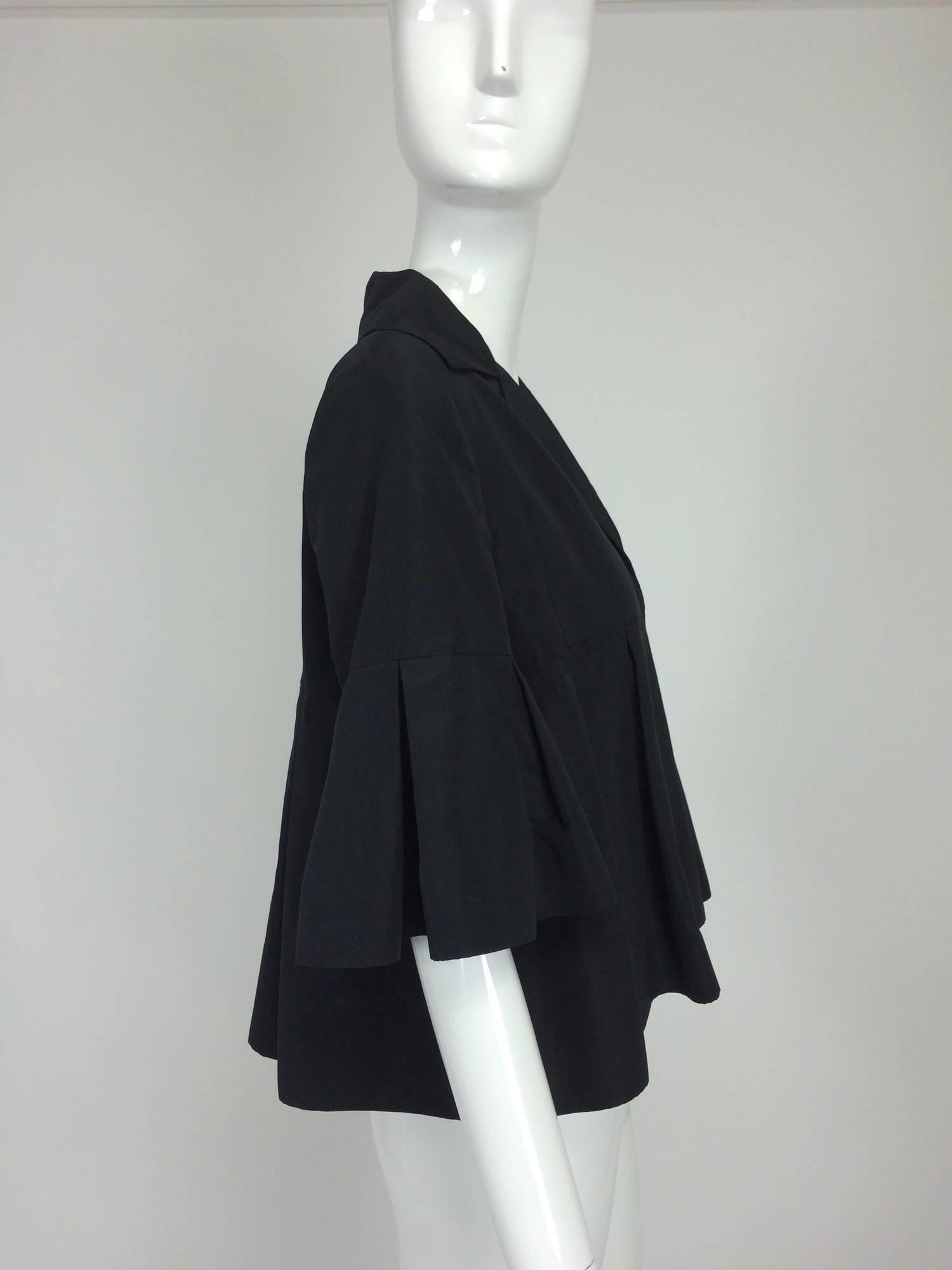 Christian Dior black silk cropped pleated jacket with pleated sleeves...Cropped jacket has a notched collar and yoke front and back...The jacket falls in open pleats below the yoke...The sleeves fall in open pleats beginning at mid upper arm and end