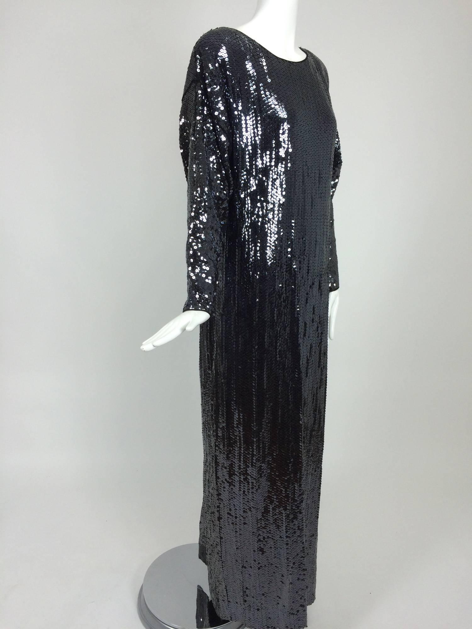 Halston, glittery black sequin bat wing evening gown from the late 1970s. Bateau neckline gown is trimmed with satin facings, long bat wing sleeves taper to the wrist. The dress has a deep sexy center back vent for ease in walking. Covered in inky
