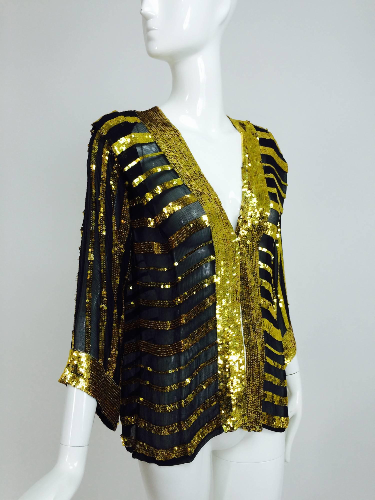 
From the late 1970s a Sweelo black silk chiffon kimono style jacket with horizontal bands of bright gold sequins...The front facings and jacket cuffs all have a wide band of sequins...Open front jacket, unlined...Unworn...Fits like a size