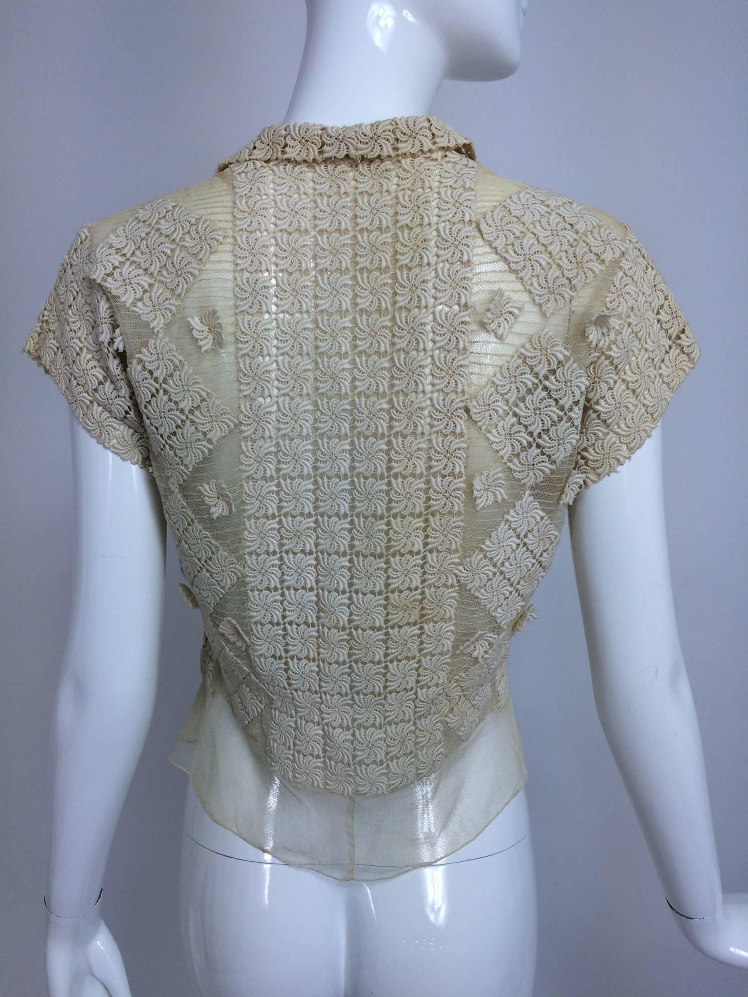 A beautiful 1930s blouse of sheer cotton tulle in cream with applique lace done in an all over design...Short sleeves, button front closes with milky glass buttons...Slightly fitted with tulle peplum...Fits like a size small...

In excellent