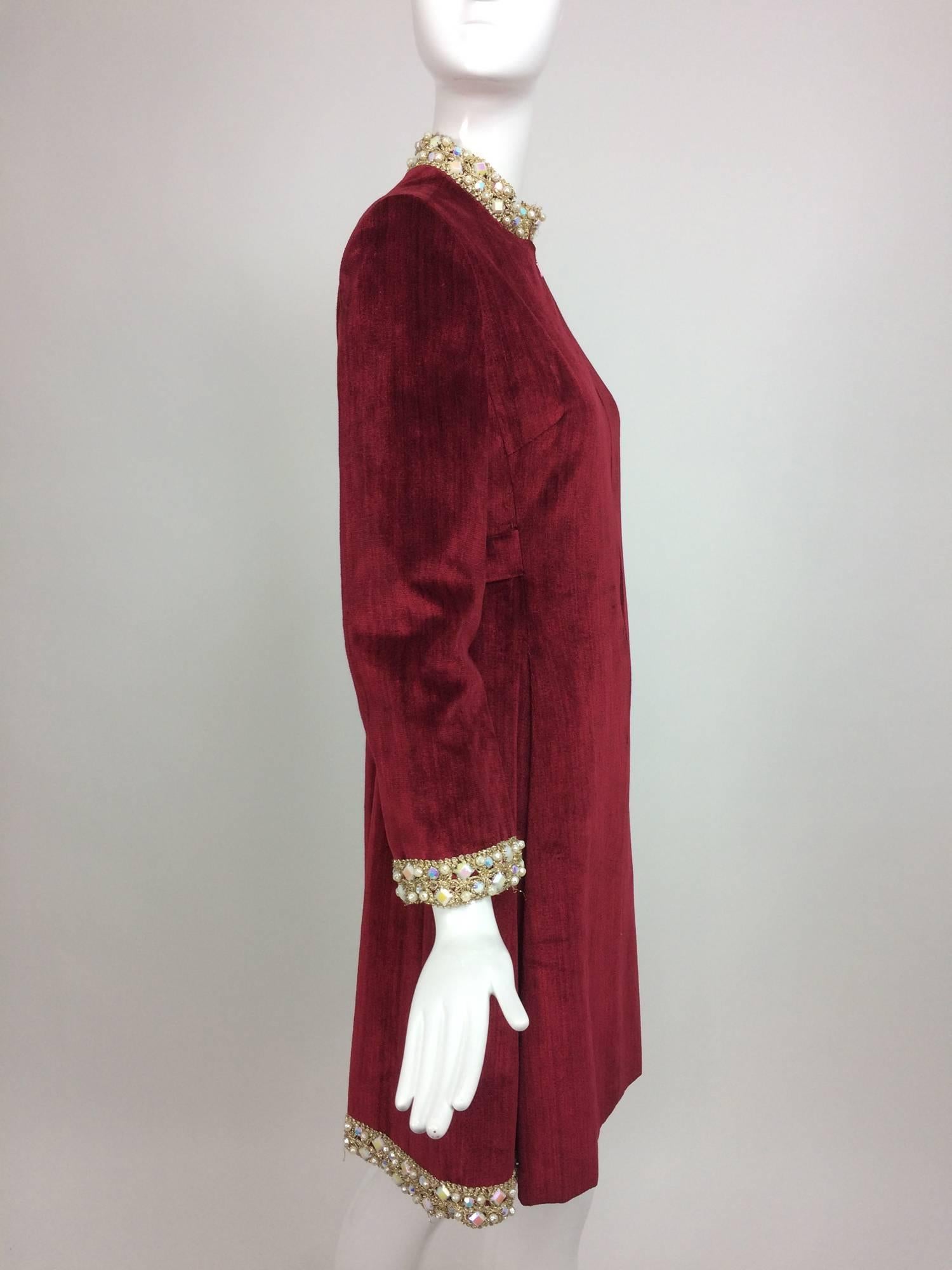 Garnet red silky cotton velvet, jewel trim Mod dress 1960s...Gold cord and jewels at the stand up neckline, cuffs and sides & back of the hem...The dress has a hidden zipper at the front and closes with hook and eyes at the neck front...Long sleeves