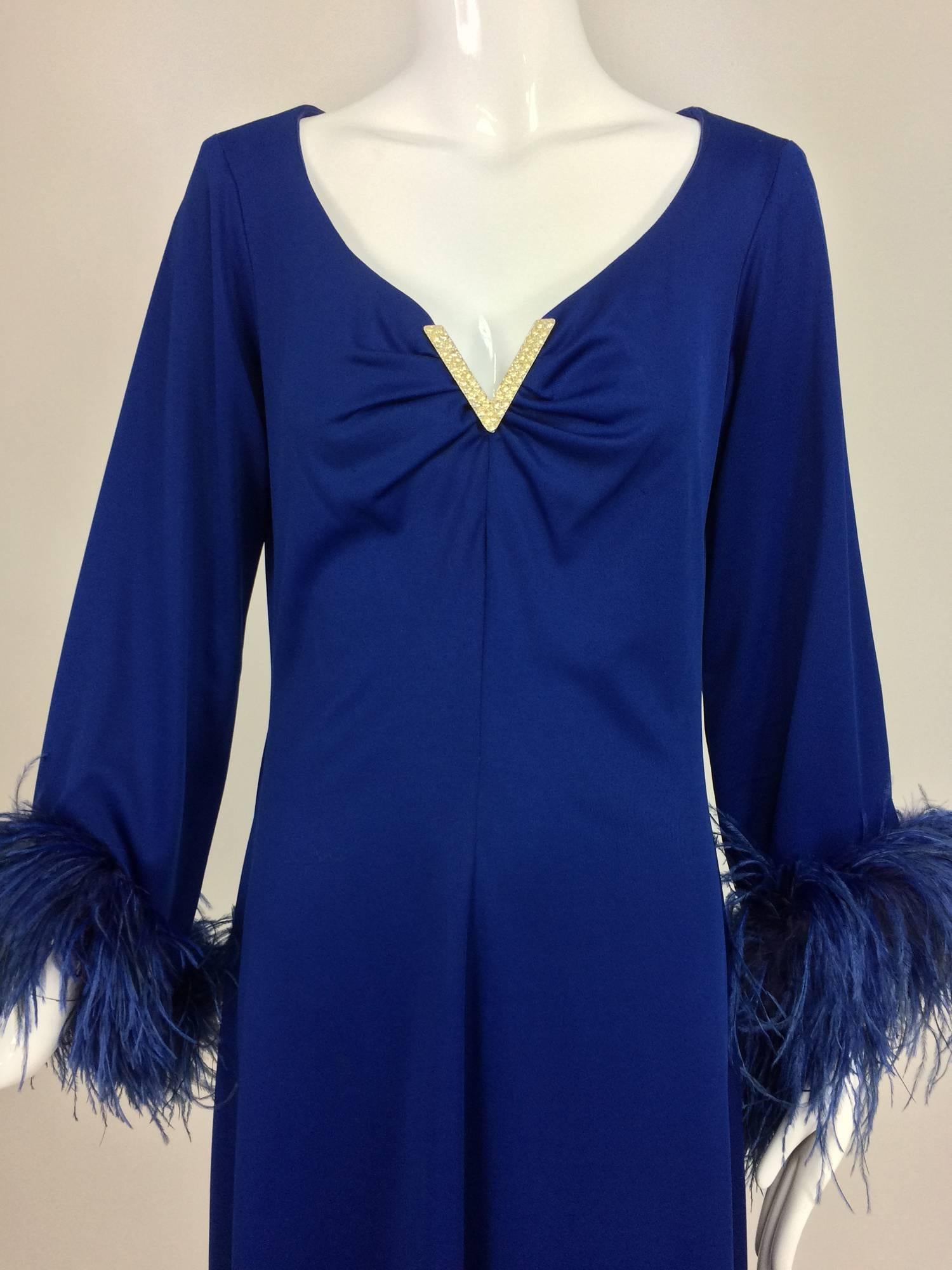 Silky electric blue jersey (poly blend) maxi dress from the 1970s...Plunge neckline has a silver metal rhinestone V pin at the bust plunge...Long sleeves with bell sleeves are trimmed with feathers at the cuffs...The dress is A line shape with