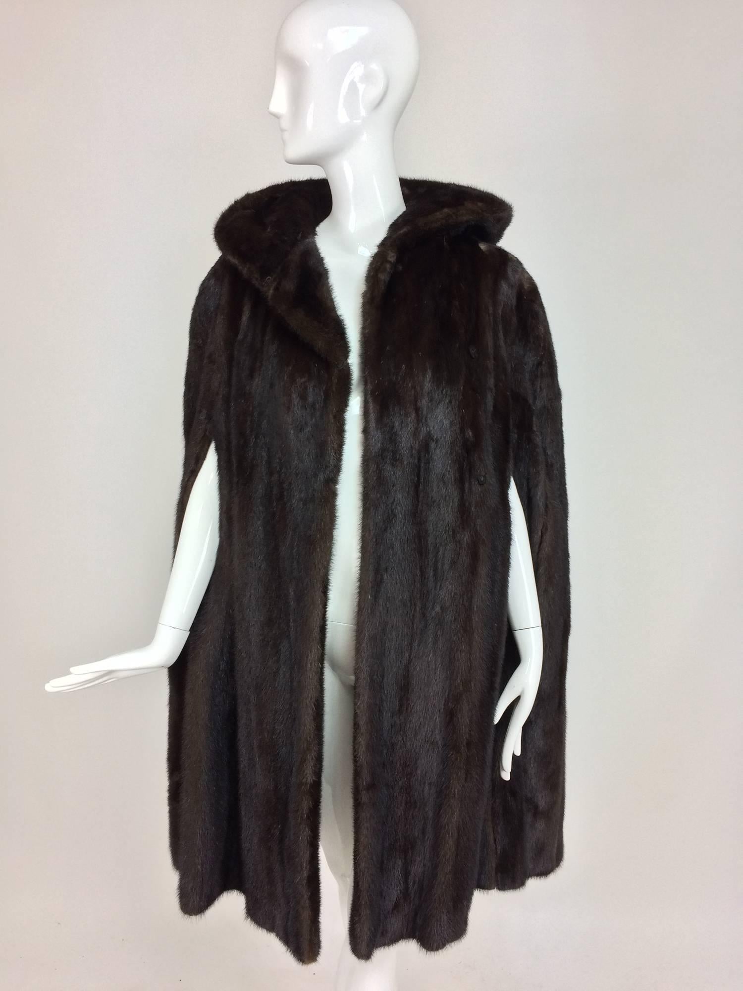 Unique and rare to find! Dark mink fur hooded cape from the 1960s and in excellent condition...Perfect length for cocktail dresses or thigh high boots...Dark glossy mink cape has arm openings at the front and closes with hook and eyes...The attached