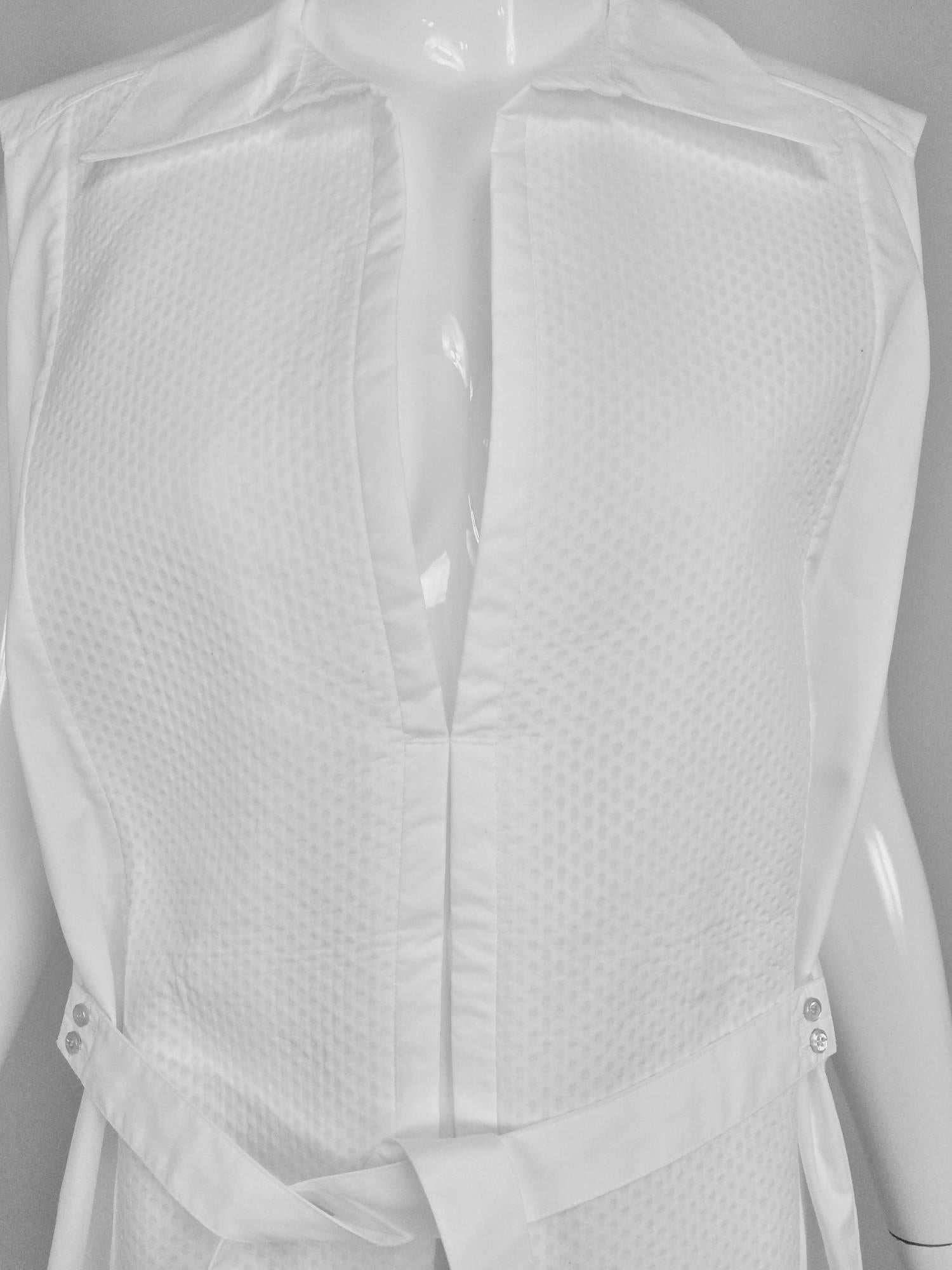 Balenciaga sleeveless white cotton pique belted tunic 38...Sleeveless tunic with wing collar, pique bib front that is cut very deeply with an inverted pleat below...Below hip length the tunic is loose fitting...Button on ties at each side
