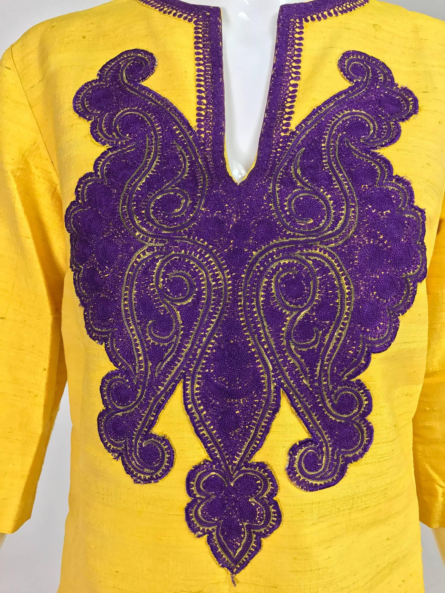 Saffron raw silk tunic or mini dress from the 1960s...V neck dress has flared elbow length sleeves, A line shape and darted bust...Unlined it closes at the back with a metal zipper...Vibrant slubbed silk has a banded neck opening trimmed with purple