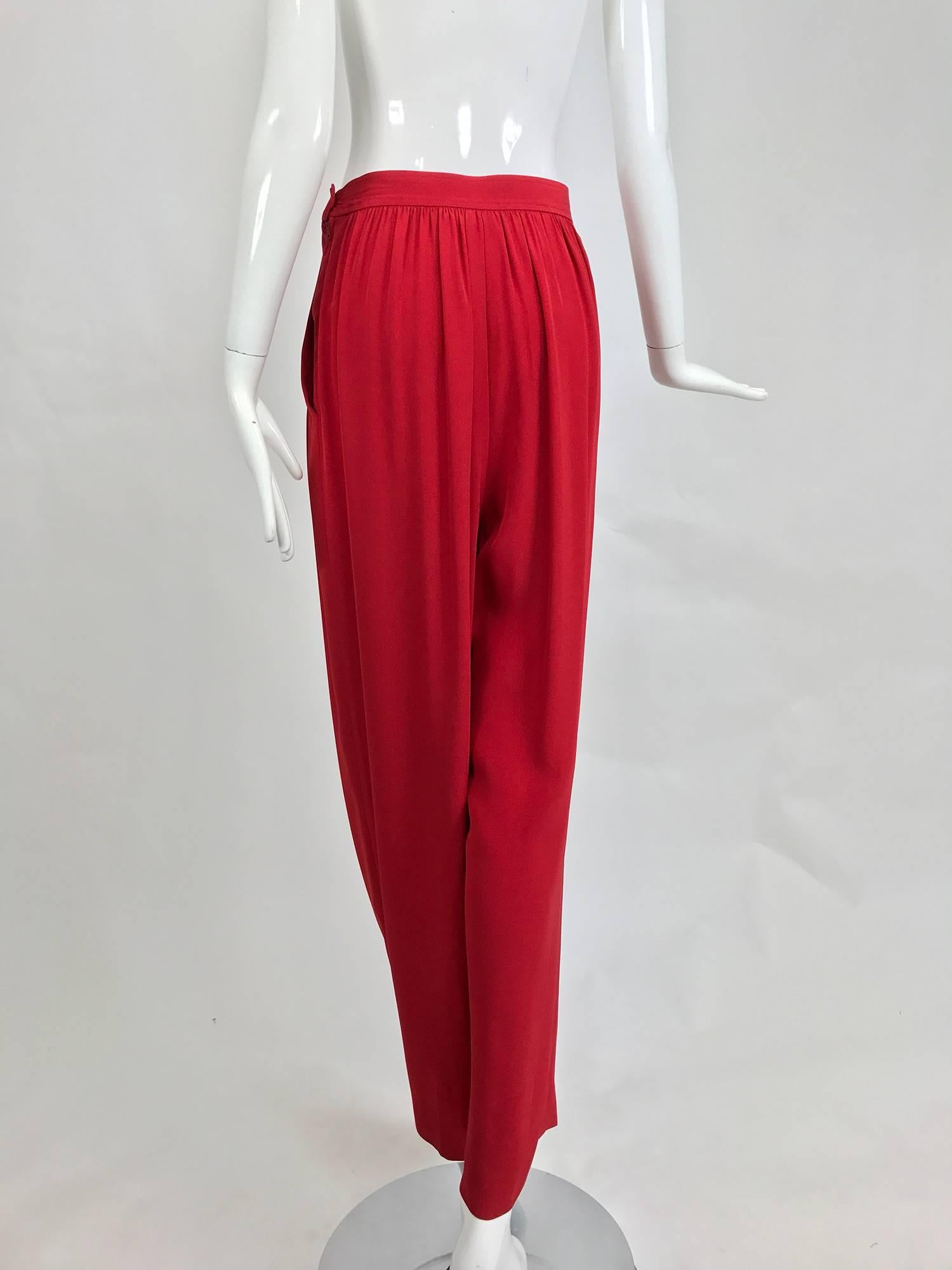 Vintage Yves Saint Laurent candy apple red satin back crepe full leg trousers from the 1990s...These amazing trousers have a banded button zwaist and close at the side with a zipper, curved hip side pockets...The front features open pleats...Full