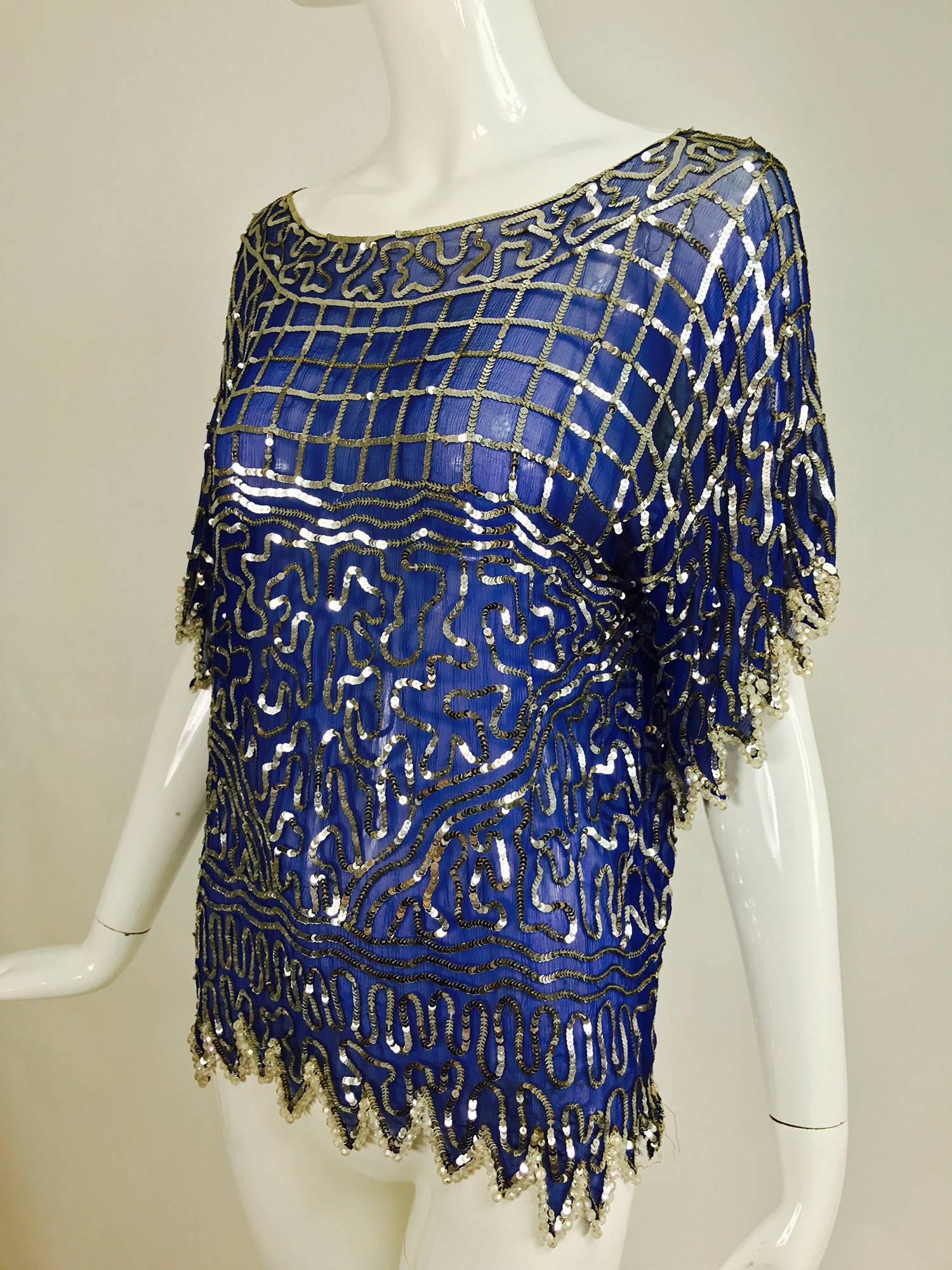 Swee lo blue silk silver sequin and beaded top from the 1970s...Royal blue silk chiffon is covered in silver sequins done in grids and swirls...Bateau neckline...Elbow length sleeves and hem form crystal bead trimmed saw tooth hems...Pull on top is