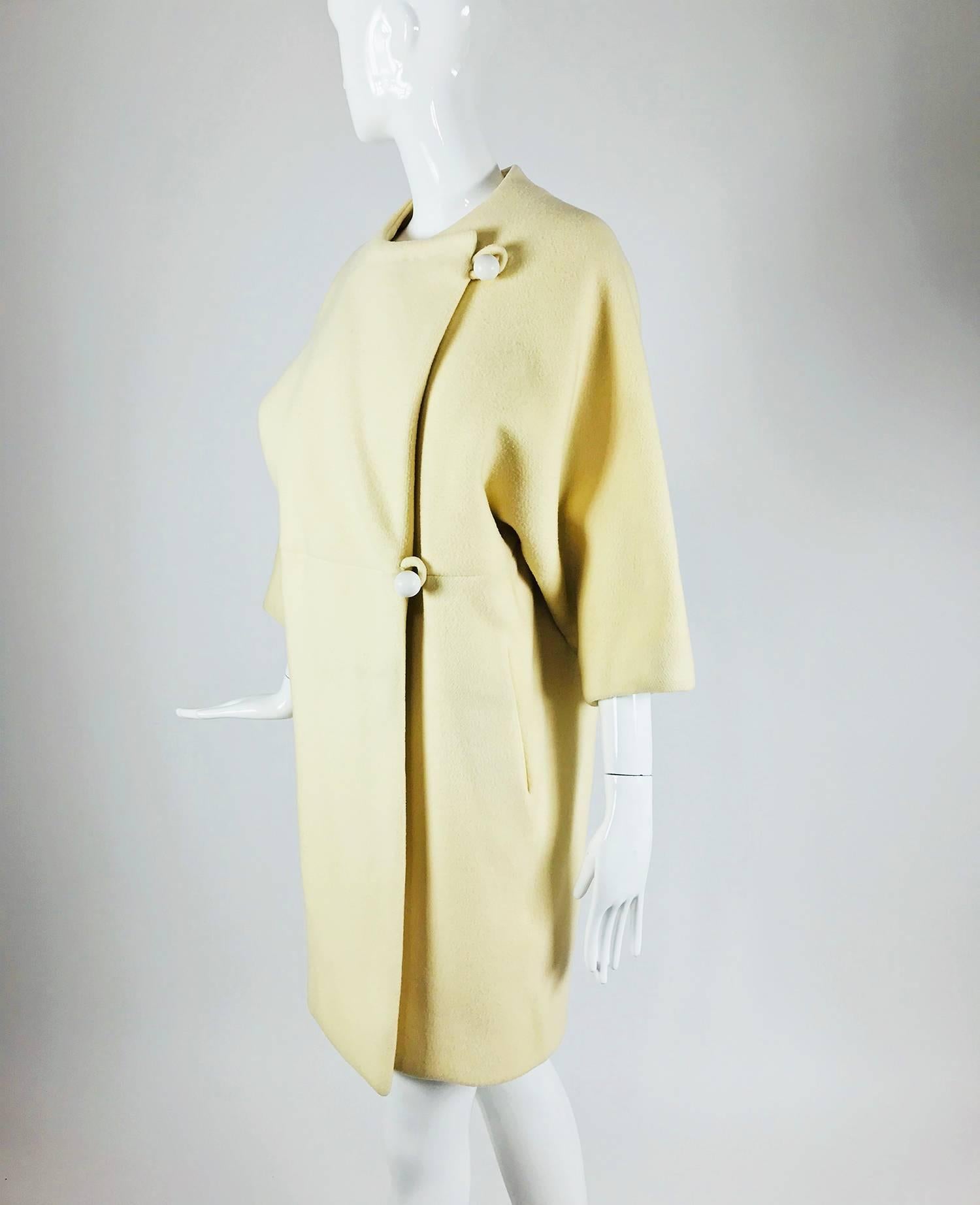 Vintage Teal Traina Winter White bat wing two button coat from the 1960s. Jewel neck coat closes at the side with two large white ball buttons and self loops. Laying flat this coat has bat wing sleeves, there is a horizontal seam at the approximate