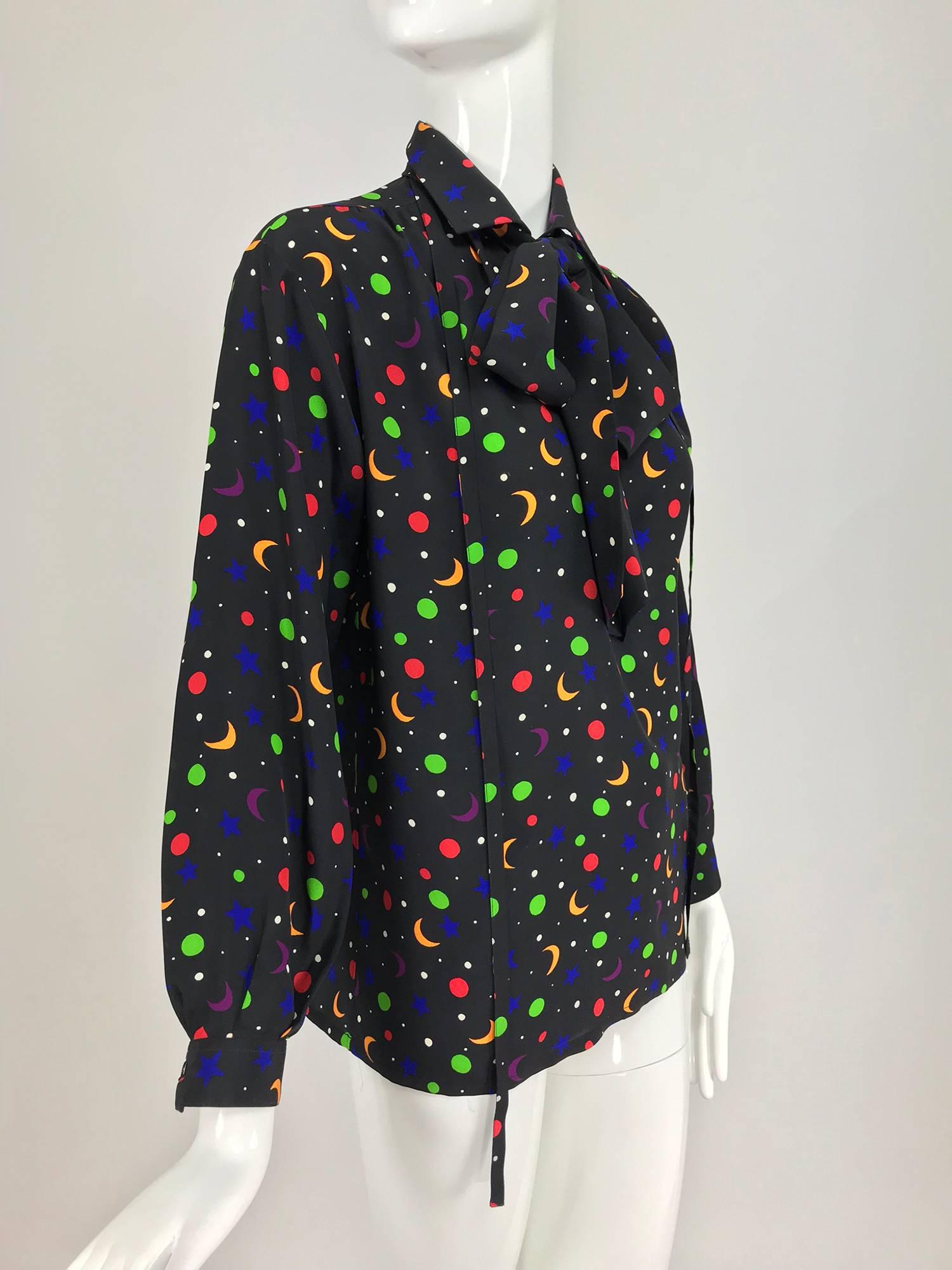 Yves Saint Laurent moon and stars silk blouse 1979 documented...Pussy bow blouse in an Iconic print from Yves Saint Laurent...Black silk is scattered with boldly coloured moons and stars...The blouse features Long sleeves with button cuffs, button