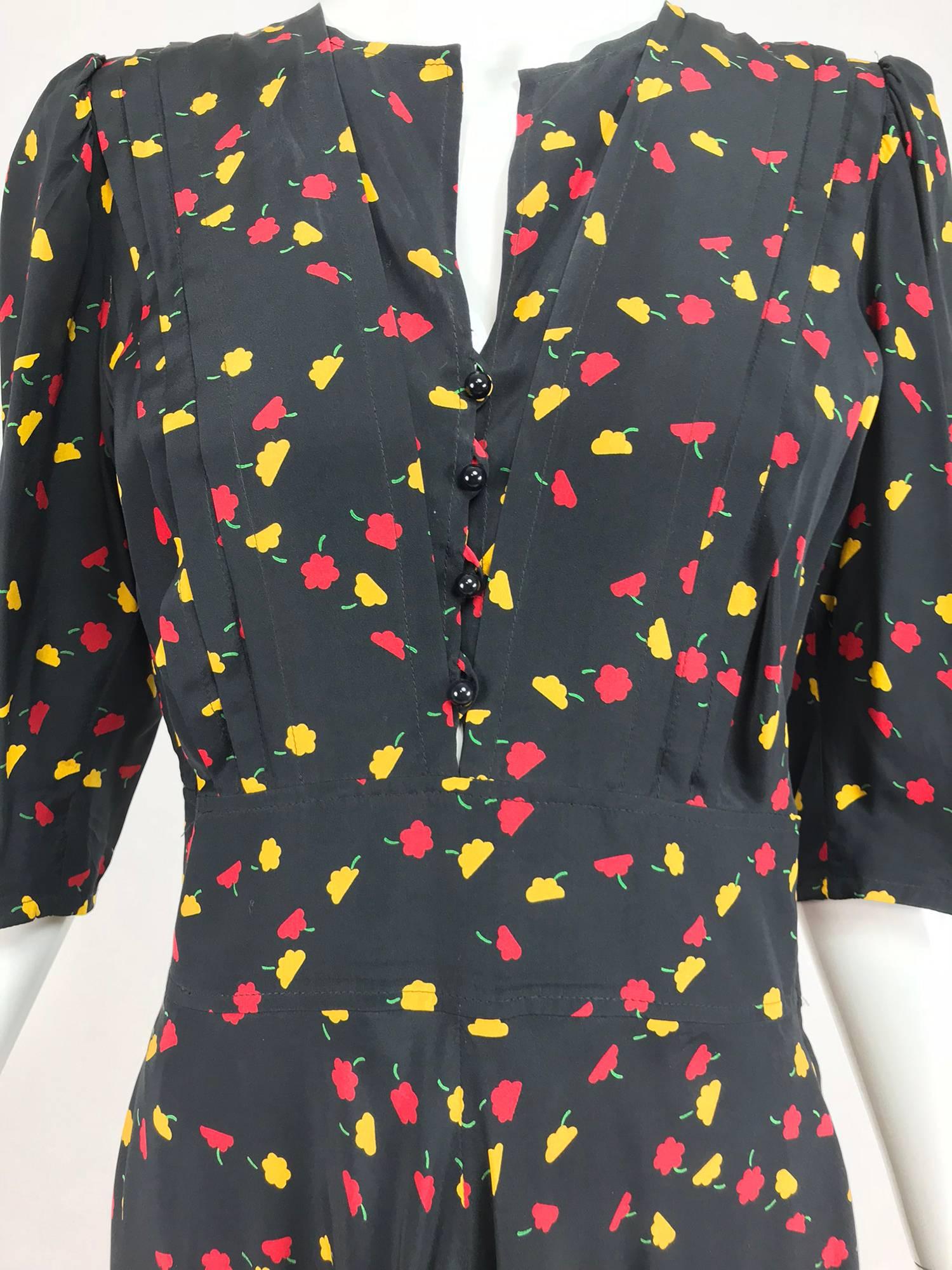 Ungaro floral print silk day dress from the 1970s...A summery dress in black silk with brightly coloured flowers scattered throughout...The jewel neck dress closes at the front with buttons and loops, elbow length sleeves and a semi fitted