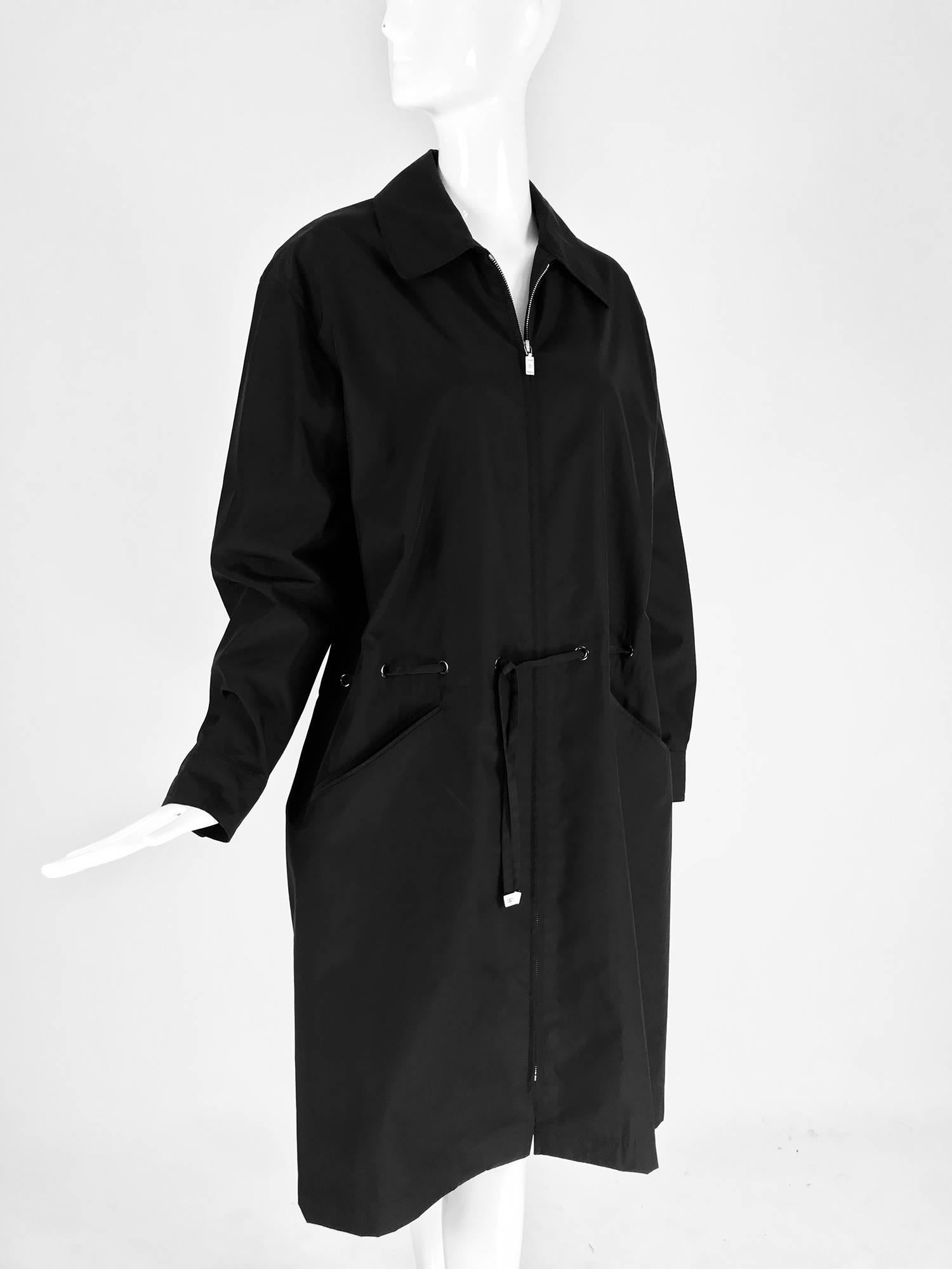 Chanel black zip front draw cord waist rain coat 1998P.  Stylish raincoat fabric is cotton with spandex and polymide, feels like mid weight nylon. Zip front coat has collar and a draw cord waist that ties at the front with silver logo tab ends. Yoke