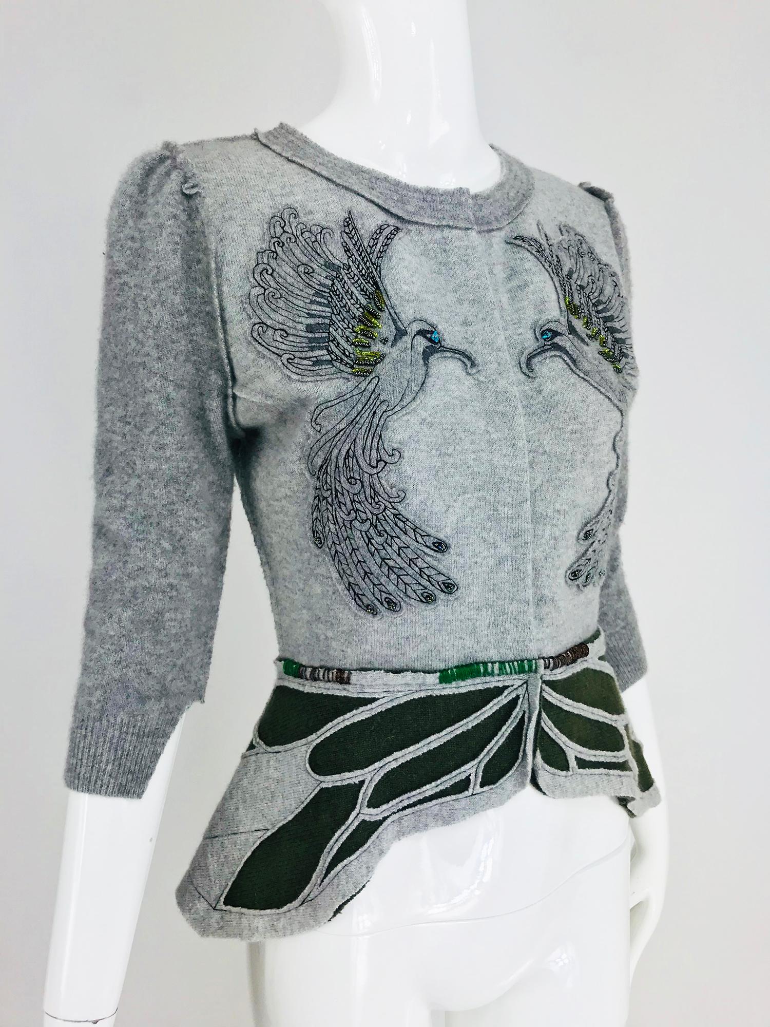 Koi Suwannagate cashmere bird applique sweater, artisan style sweater in pale grey fleck cashmere with embroidered birds appliqued at each front panel. The elbow length sleeve sweater has a peplum waist, the peplum has inset panels of moss green