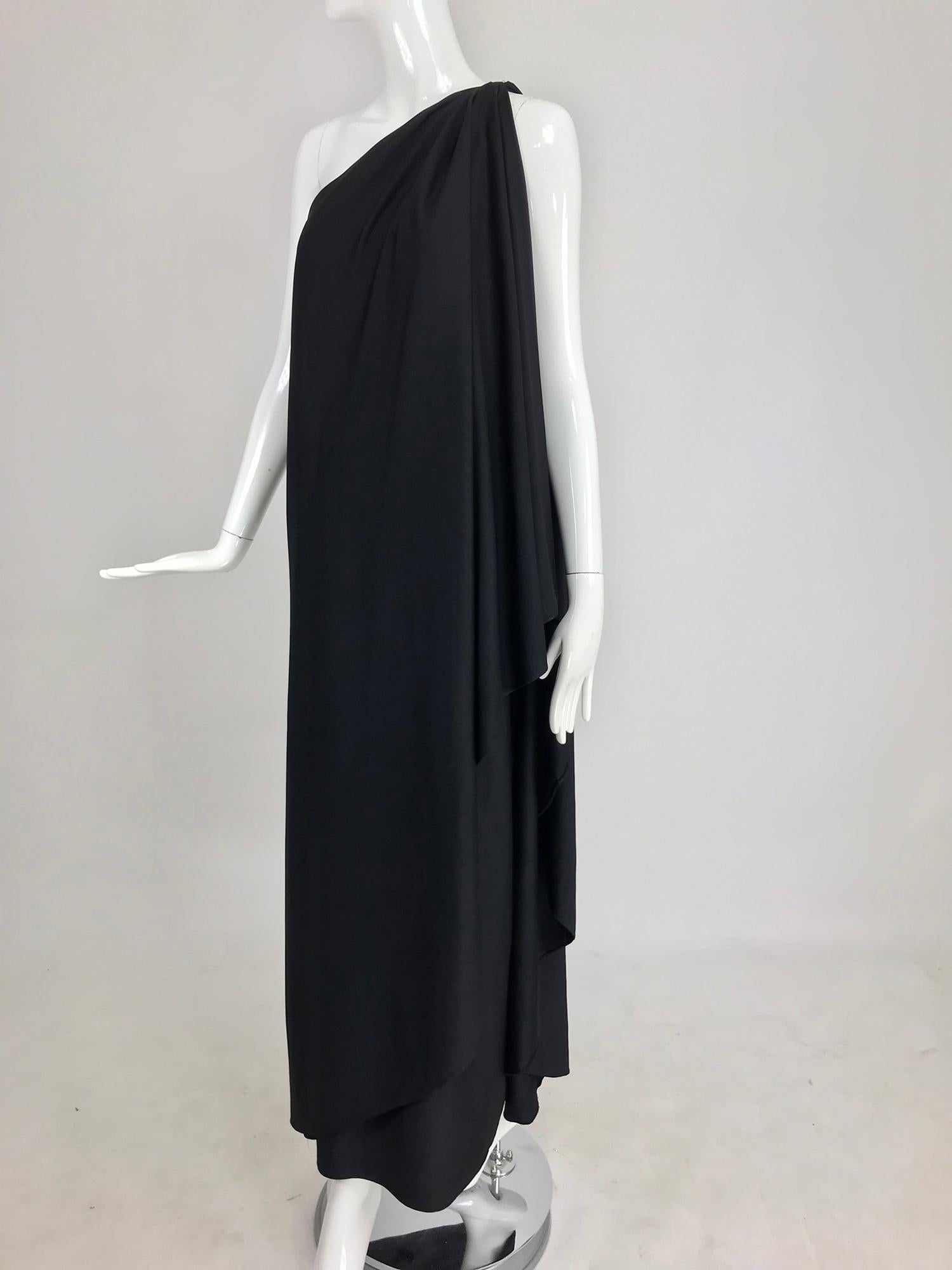 Halston IV one shoulder black jersey draped maxi dress from the 1980s. Goddess style gown closes at the draped shoulder with a hidden hook and eye, the gown wraps and drapes and is open at the side front. Side hem vent. Black poly jersey fabric