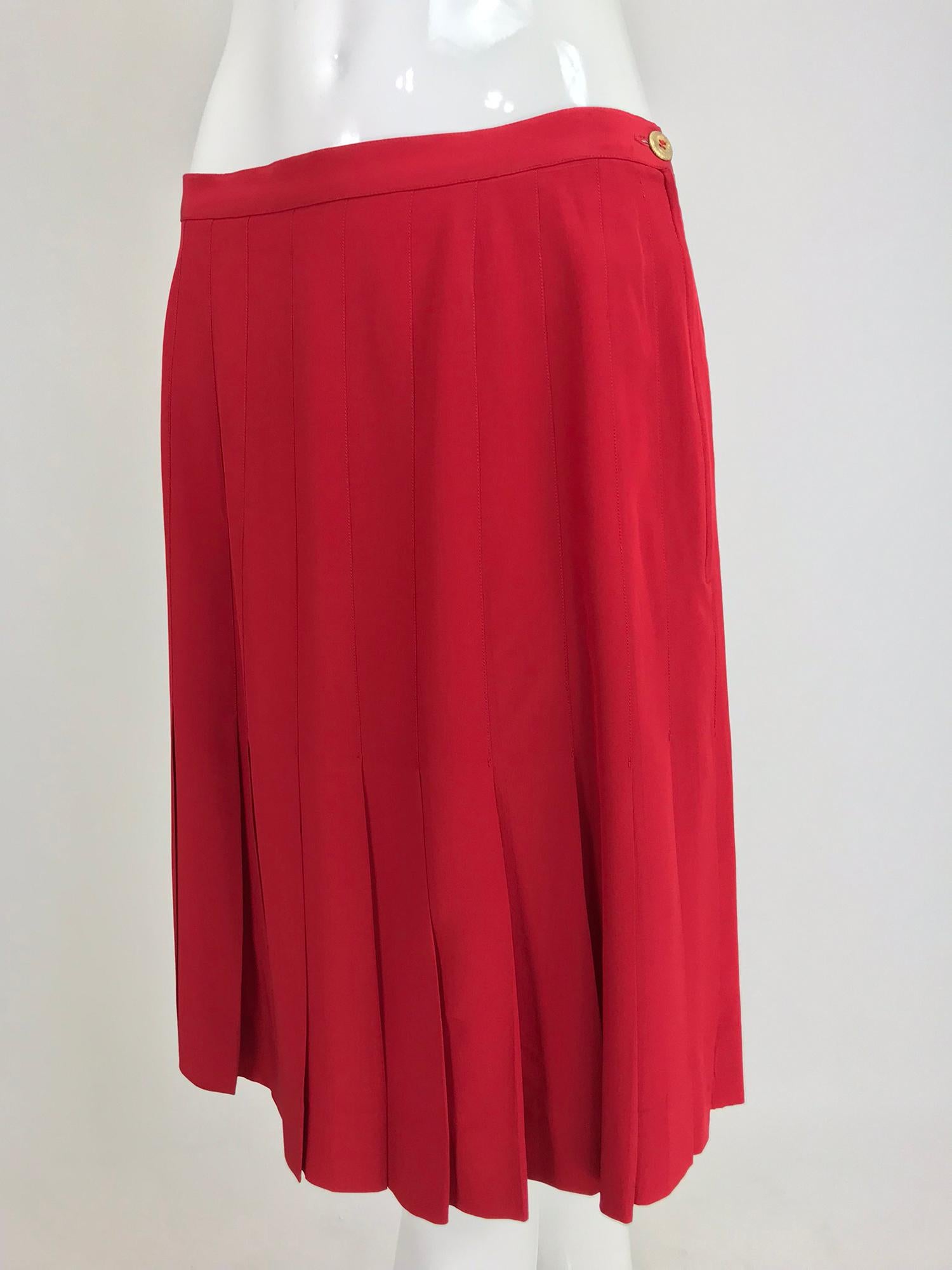 Chanel Red silk stitch down pleated skirt from the 1990s. Classic go with skirt in a candy apple red shade. Fully lined in red silk. Closes at the side with a gold button and zipper. Fits a size S-M. 

In excellent wearable condition... All our