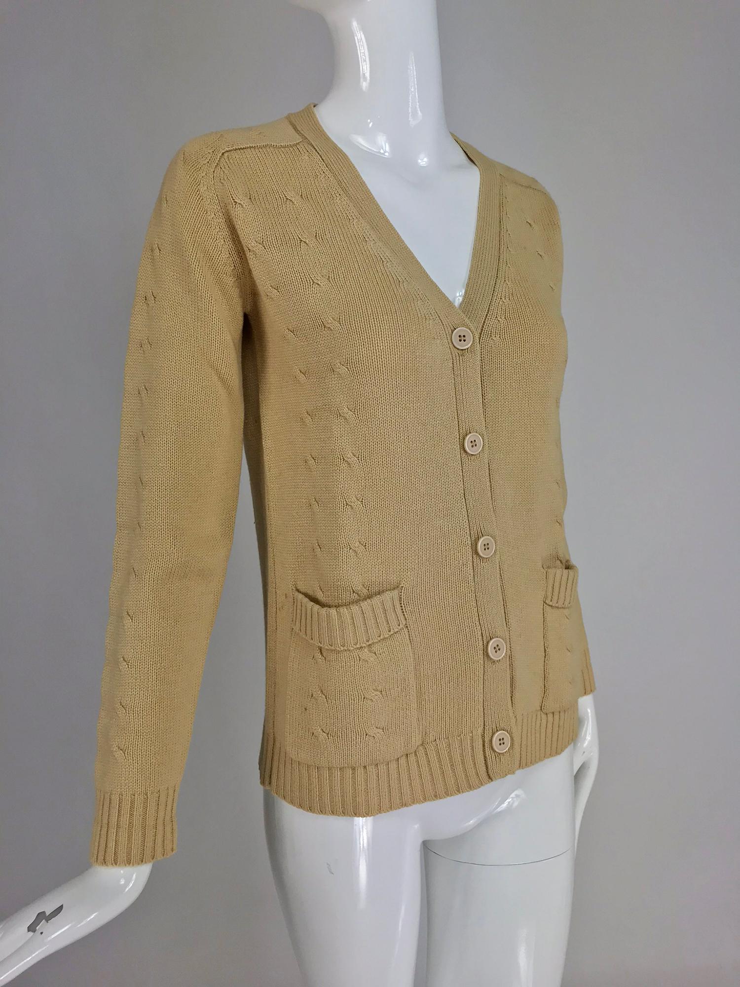 Hermes tan cashmere silk cable knit cardigan sweater from the 1960s. Boyfriend style, button front sweater with a v neckline and hip front patch pockets. The front and outer sleeves are done in a cable design. Raglan sleeve sweater is unlined. There