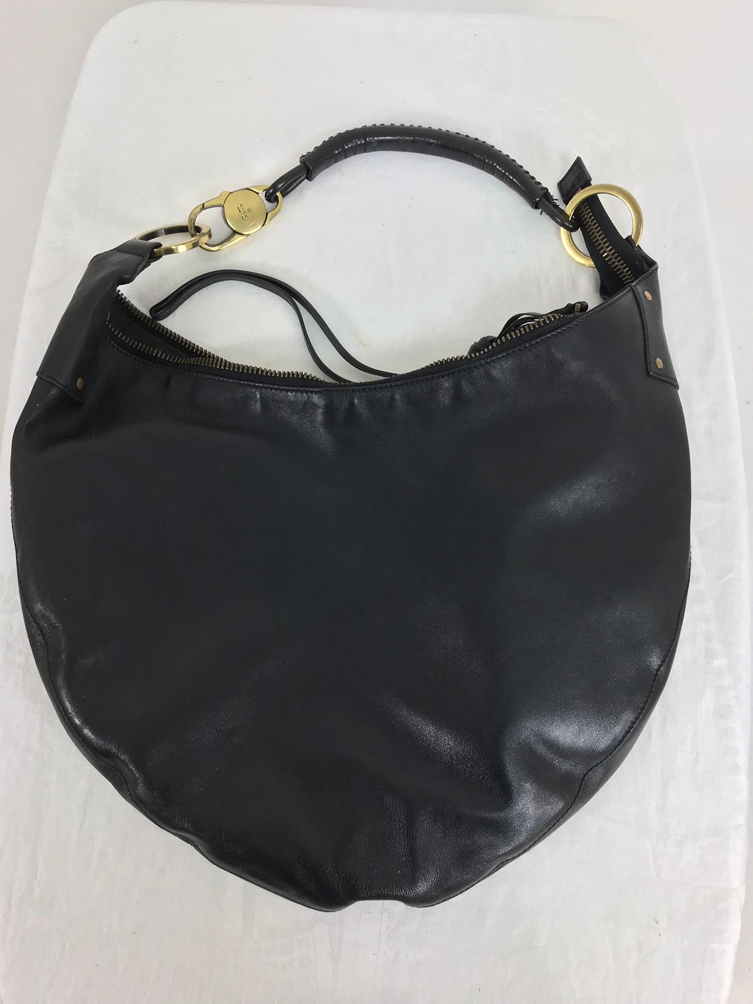 Gucci black leather shoulder bag with gold hardware. This beautiful bag looks barely, if ever worn. Laced leather shoulder strap with gold hardware, all marked Gucci. The sling shape leather bag closes with a heavy brass zipper, there are long