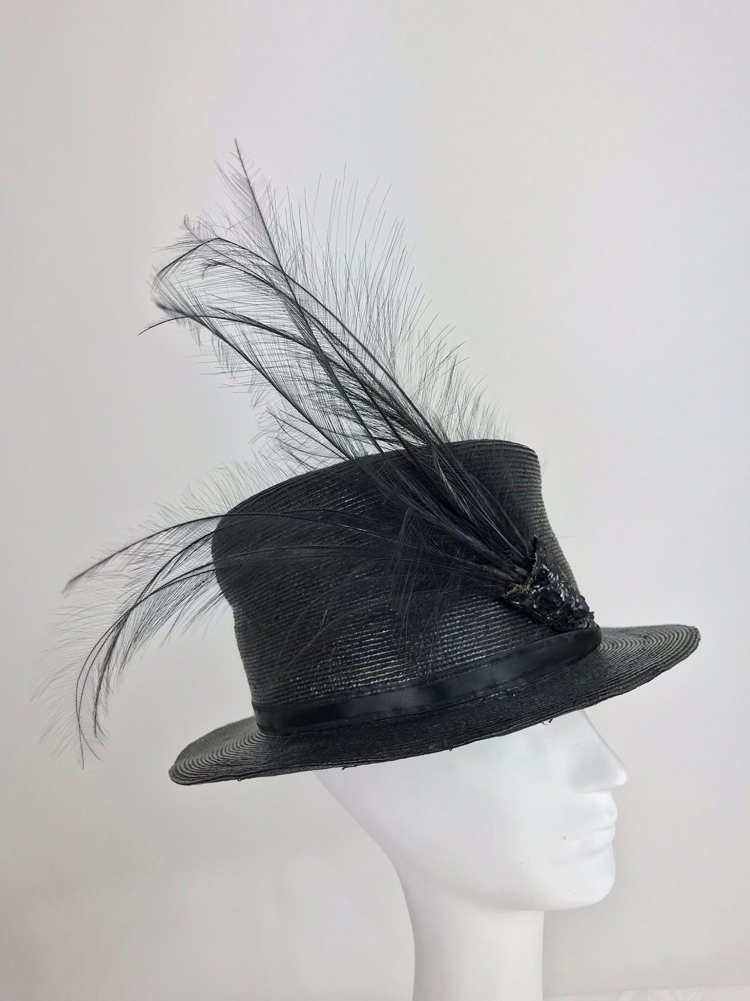 Edwardian Glazed black straw hat with Bird of Paradise feathers. Tall crown hat with a narrow brim is made from a fine black glazed straw. The hat has a narrow ribbon band (replaced) with the original black sequin decoration that holds the plume of