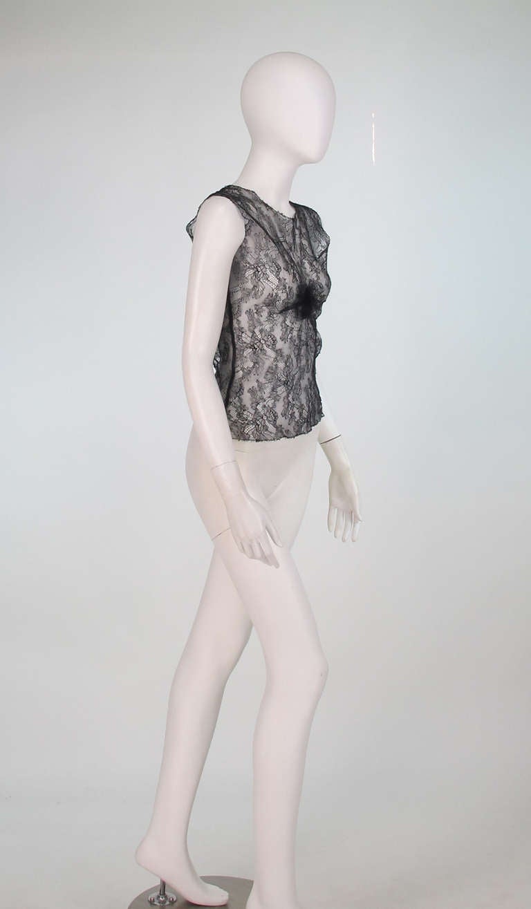 Chanel black lace sleeveless top from 2004A collection. Sheer lace pull on top is unlined. The neckline, hem and arm openings are trimmed in lace. There is a center front rosette gathering of lace. Fits like a modern 2-4.
 In excellent wearable
