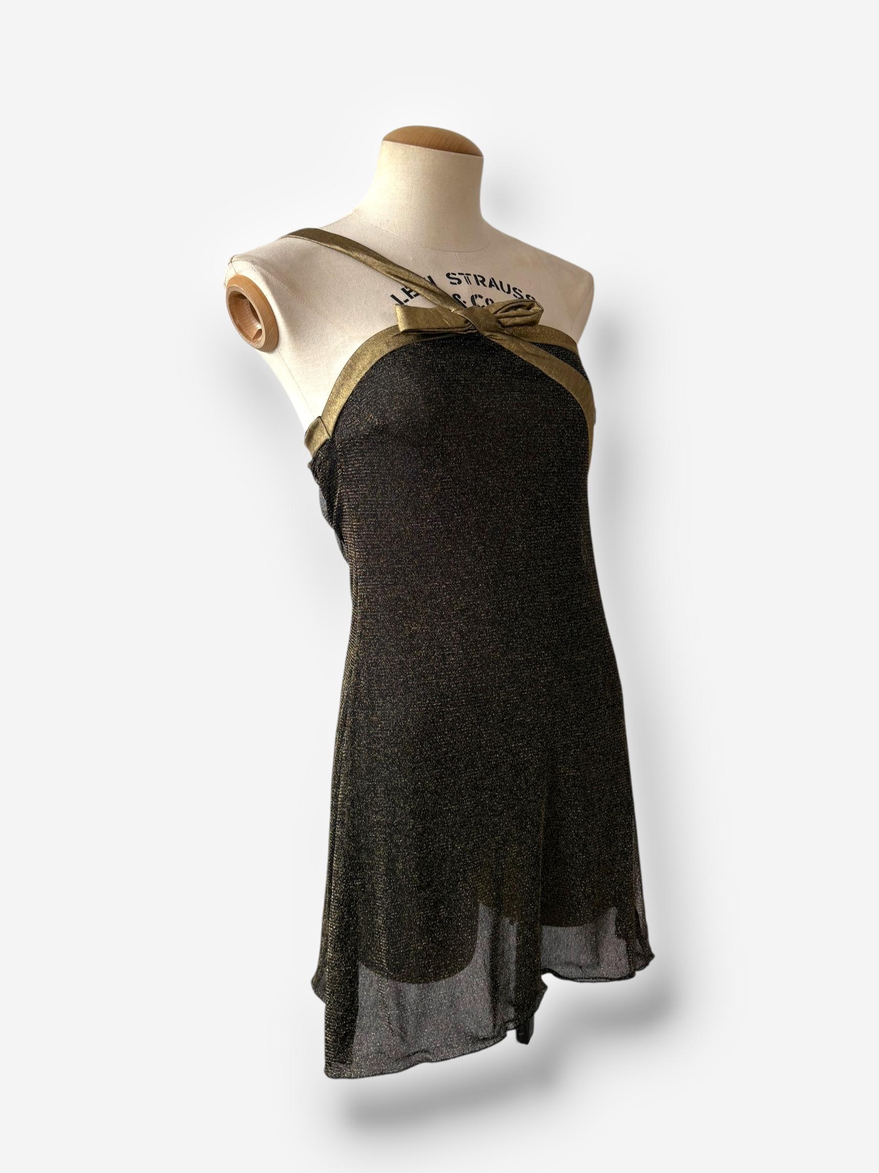 Cette mini robe vintage de John Galliano reflète son flair pour le drame et le luxe. Fabrice en tissu métallisé noir et or scintillant, la robe présente une silhouette A-line avec un ourlet volanté et un détail de cravate dorée métallique à