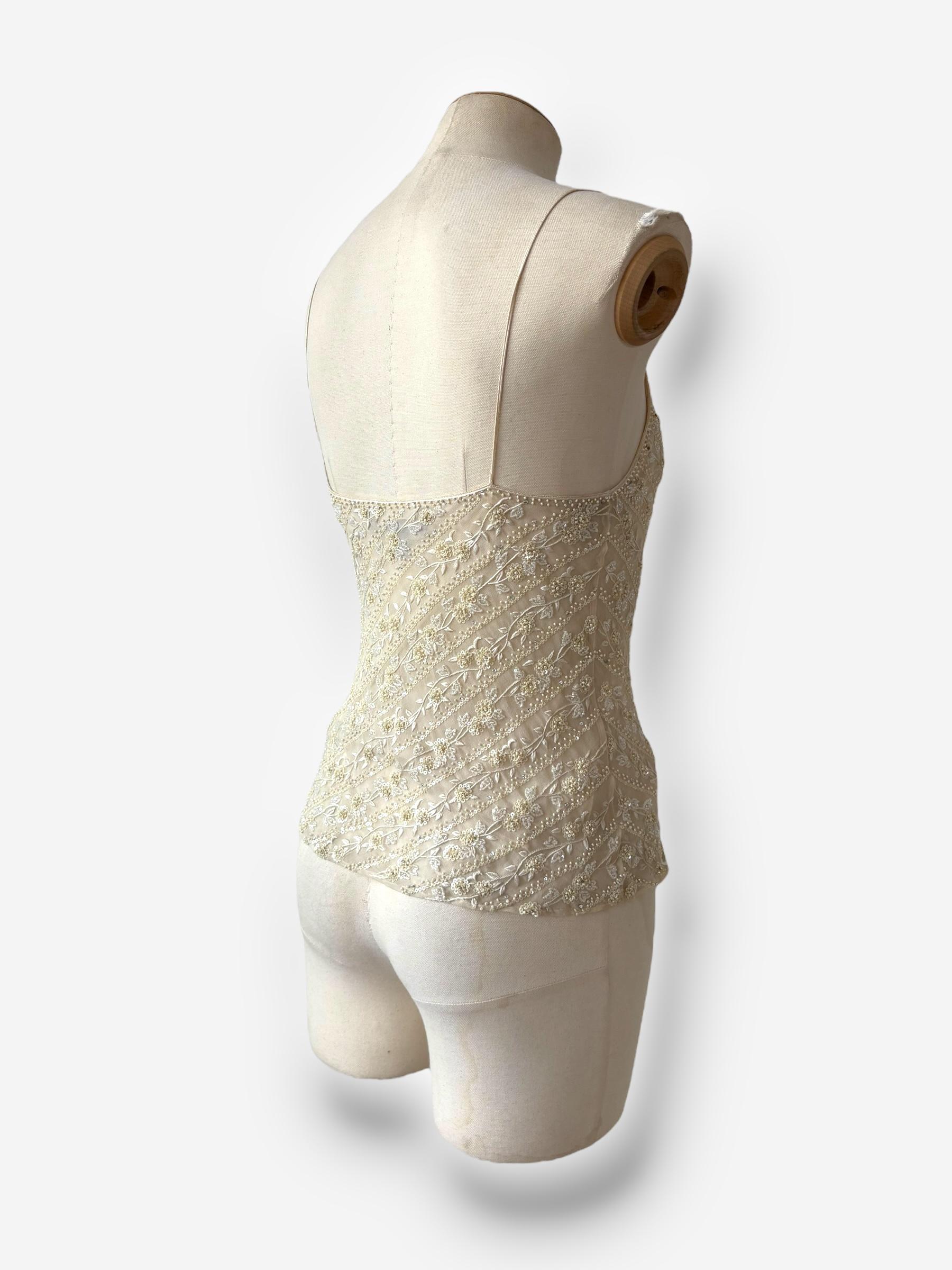 

u2028Este top de seda color crema, exquisito ejemplo de los trajes de noche de Ralph Lauren de finales de los 90, está ricamente adornado con delicados abalorios. El corte minimalista equilibra la intrincada textura de la superficie, dando como
