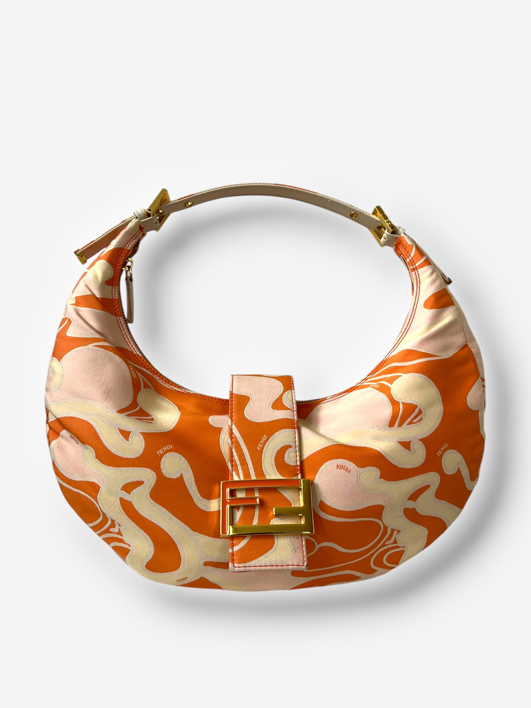 
Diese Vintage-Umhängetasche von Fendi ist ein kühnes Archivstück mit einem hypnotischen psychedelischen Print auf Canvas, gepaart mit einem strukturierten Lederriemen und der charakteristischen Croissant-Silhouette. Goldfarbene Beschläge, ein