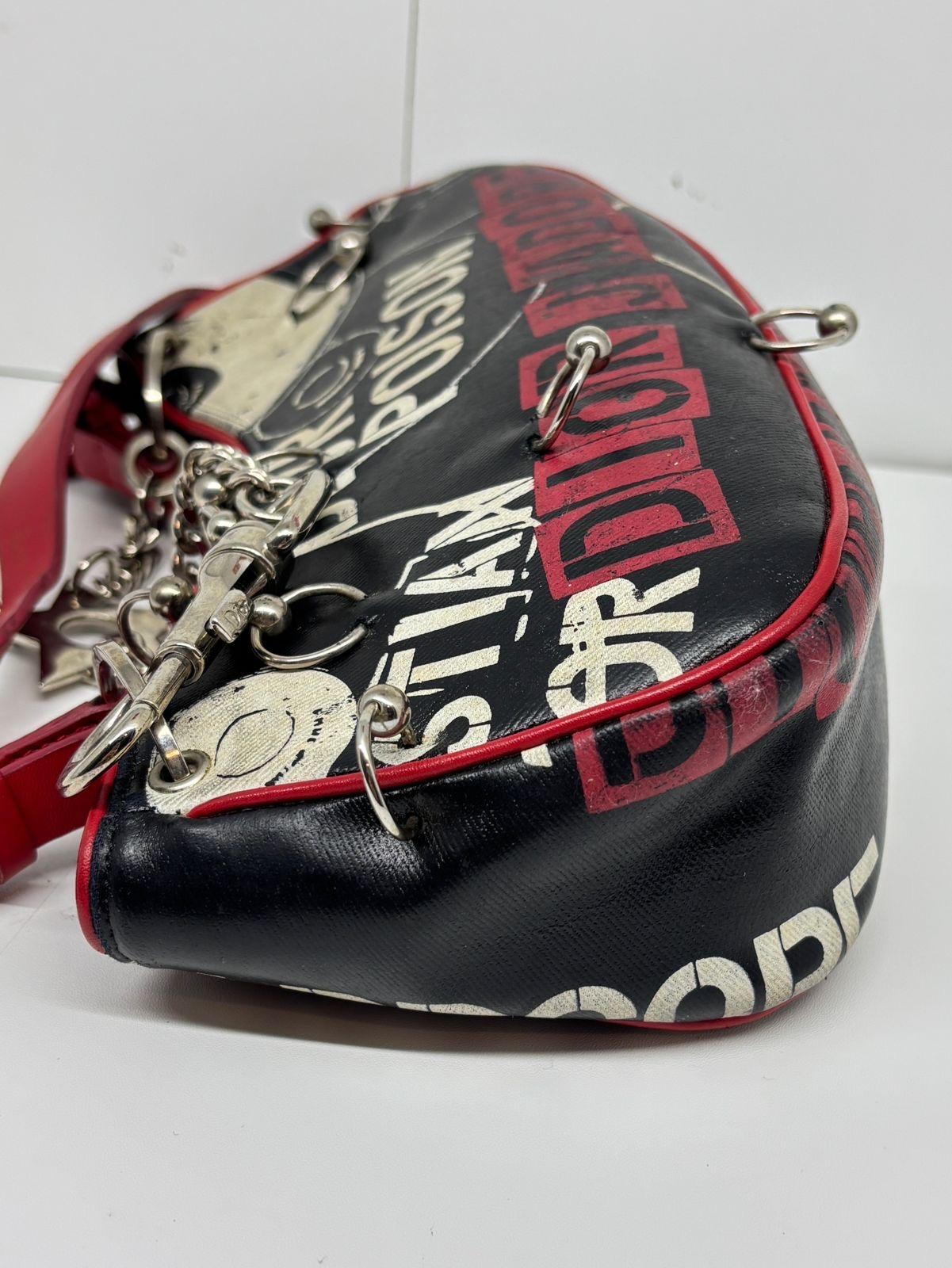 Collection iconique John Galliano pour Dior Hardcore. Tout le matériel de perçage est attaché. Rayures visibles sur la surface du sac et frottements dans les coins. Léger ternissement de la quincaillerie. Les poignées en cuir présentent également