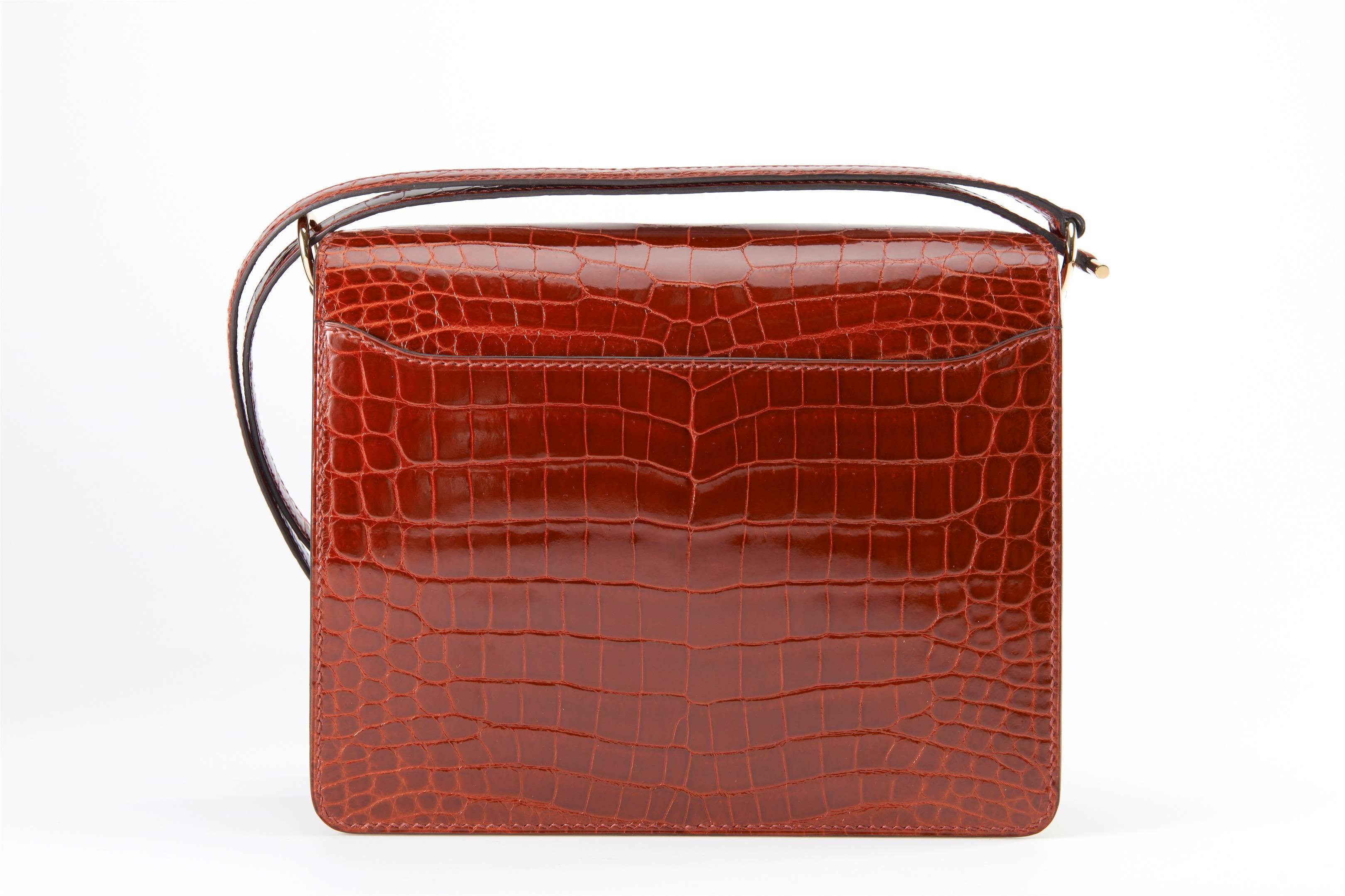 EXCLUSIVE offer - Hermes SHINY ROUGE HERMES NILO crocodile ROULIS with CAPPUCCINO LEATHER COVERING GOLD PERMABRASS HARDWARE. 

THIS BAG IS A WINNER ALL AROUND! IT IS GREAT CROSS BODY OR DOUBLED AS A SHOULDER BAG. HAS A GREAT BACK POCKET FOR A