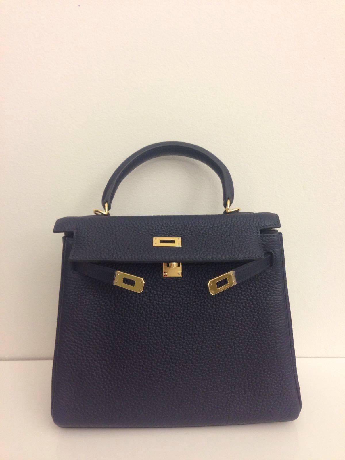 Brand Hermes, Kelly Bag, Sixe 25, Color Blue Nuit, Leather Clemence, Gold Hardware.

This Kelly comes with a raincoat, clochette, cross body strap, leather guide booklet, box and dustbag.