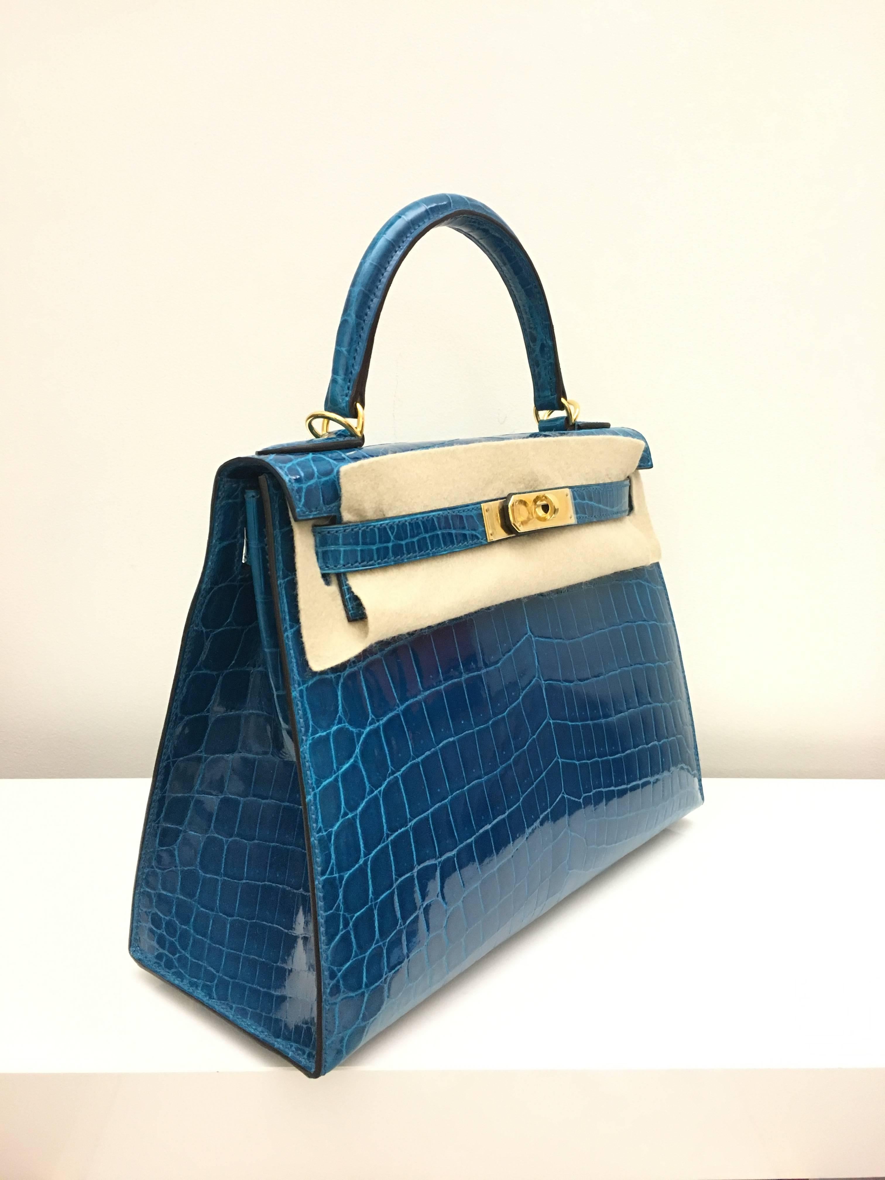 Hermes 
Kelly Size 28
Shiny Croc Leather 
Colour Blue Izmir
Gold Hardware 
store fresh, comes with receipt and full set (dust bag, box...) 
Hydeparkfashion specializes in sourcing and delivering authentic luxury handbags, mainly Hermes, to