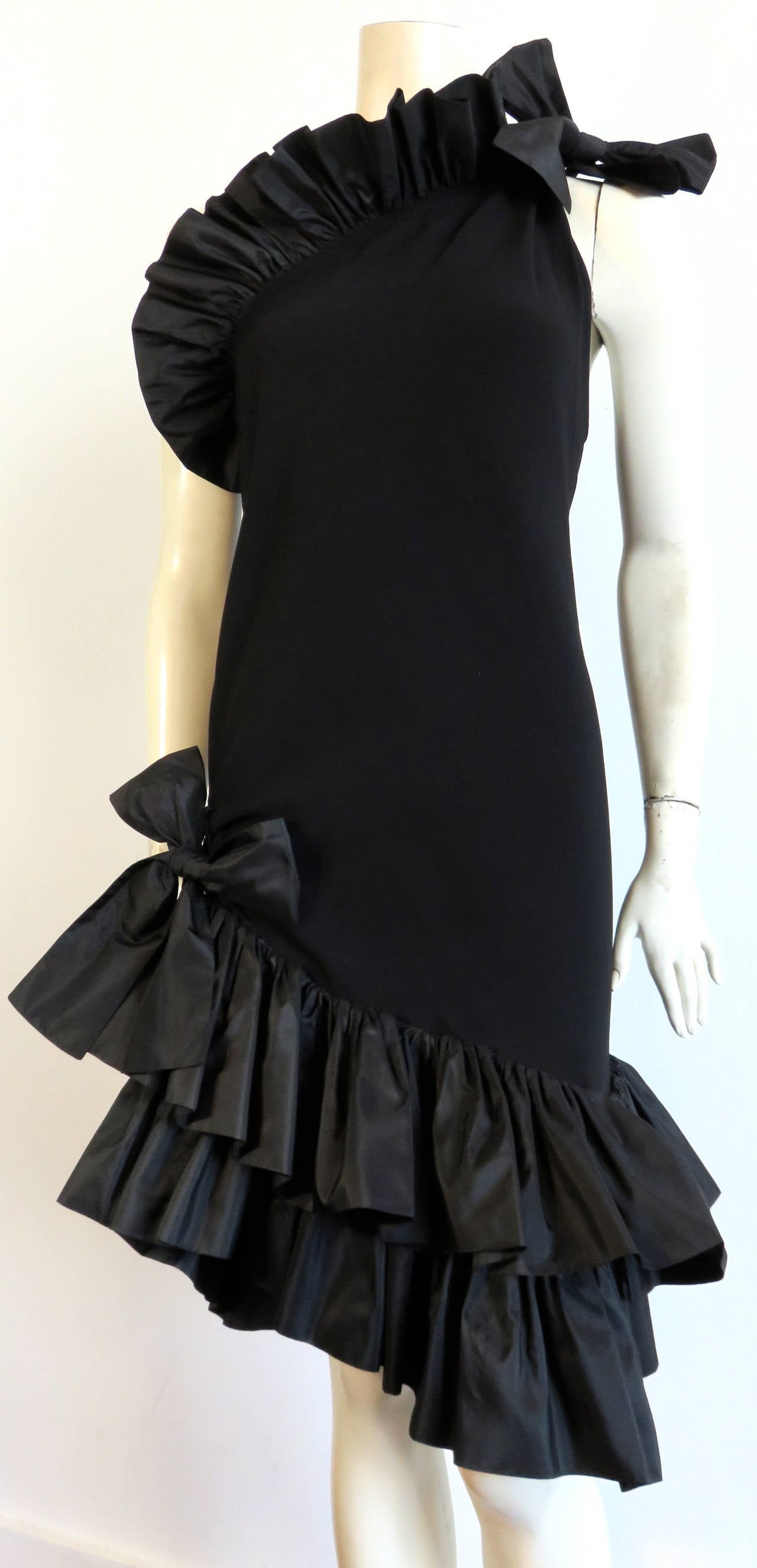 Excellent condition, 1980's YVES SAINT LAURENT Paris ruffle dress.

This gorgeous, one-shoulder, cocktail dress is made of black crepe with silky satin inner facing.  The ruffles, and bow-ties at the top and bottom the dress are made of crisp,