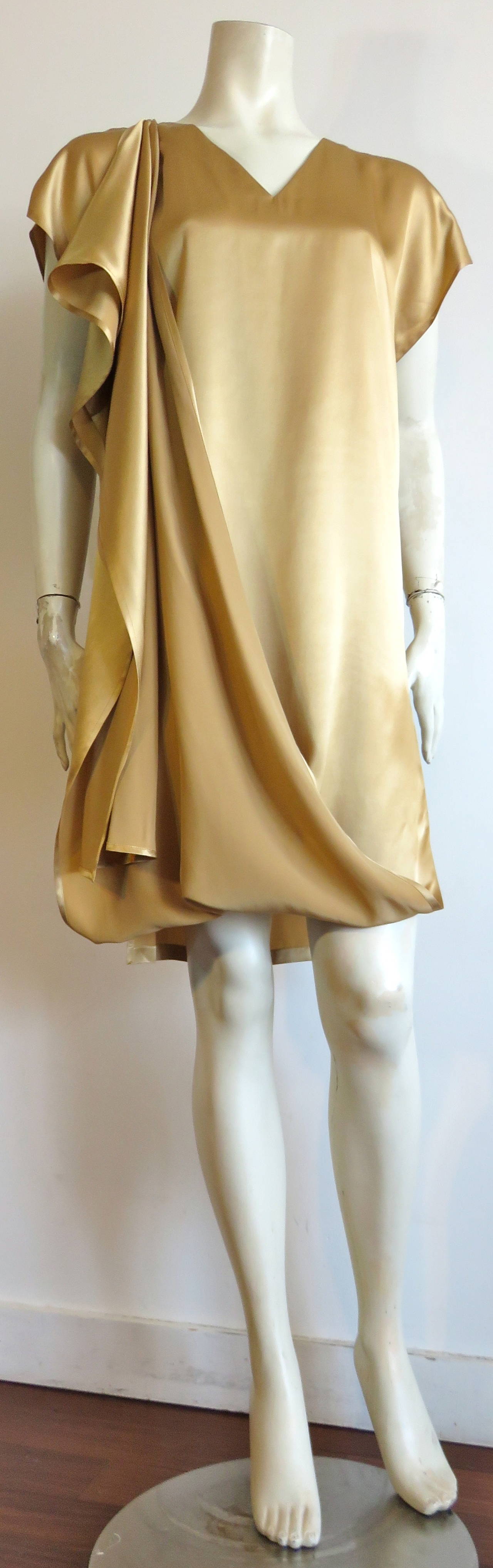 Never worn, 1990's SHAMASK COUTURE / MOSS Gold silk charmeuse dress with excellent draped front detail.

The draped front of the dress buttons down to the wearer's right shoulder, and when released the very long front panel is exposed.

Loose