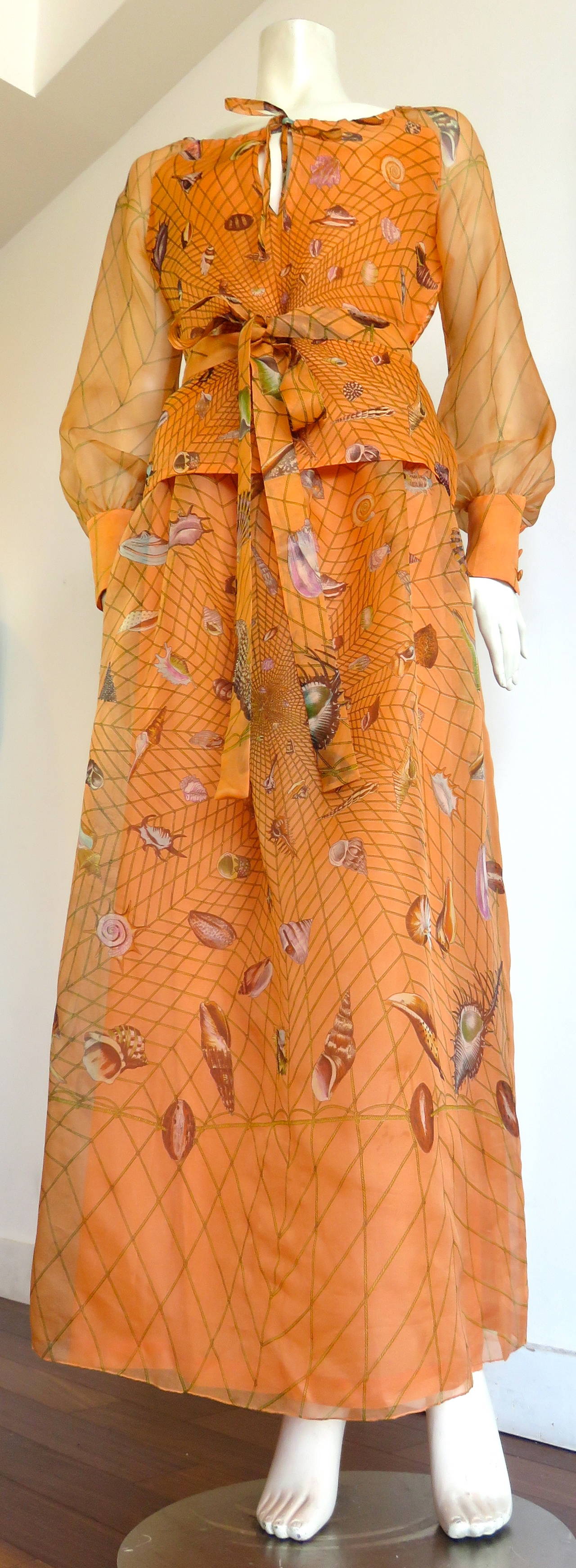 Worn once, 1970's, GUCCI Seashell printed, 100% silk organza 2pc. dress set.

Original 1970's edition of Gucci's classic seashell artwork in a gorgeous apricot/tangerine ground color comprised of a top, skirt, and matching belt/sash.

The highly