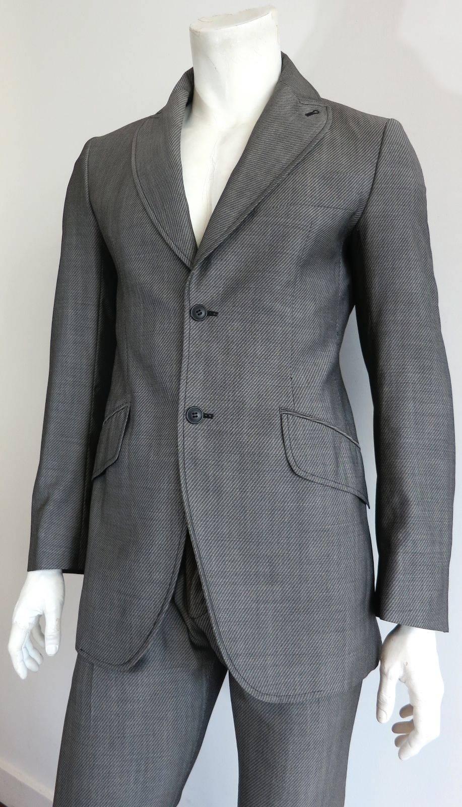 EDITOR'S NOTES:

Excellent condition VIVIENNE WESTWOOD LONDON Man gray wool & mohair, twill weave suit

Double button front closures

Signature Westwood shaped, peak lapel front with embroidered button hole

Generously sized, twin flap