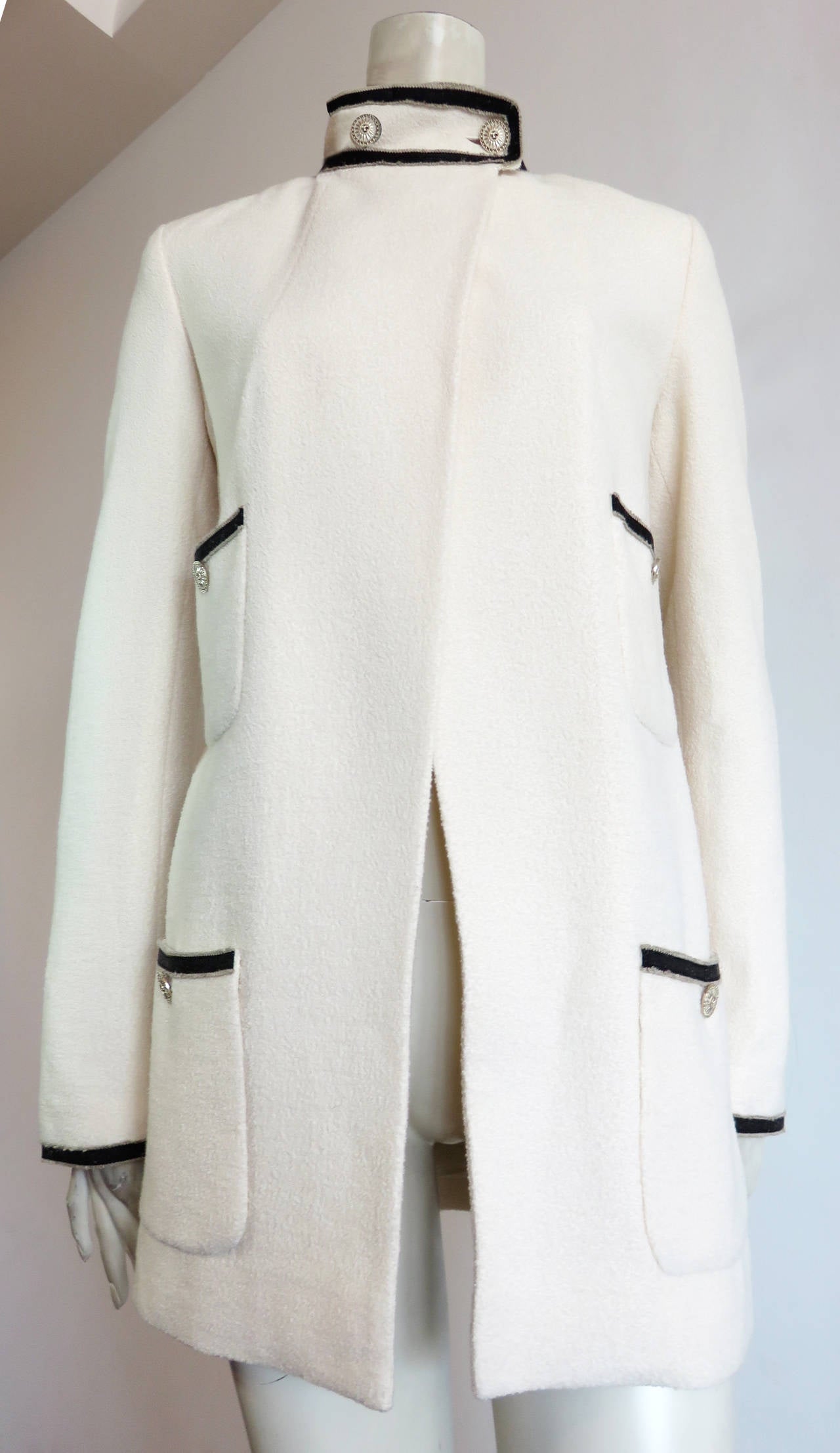 Worn once, CHANEL PARIS ivory, silk & wool bouclé coat.

This excellent condition coat features an open front design that buttons down at the banded collar neck.  

The engraved metal buttons feature 'CC' sunburst style logos with silver metal