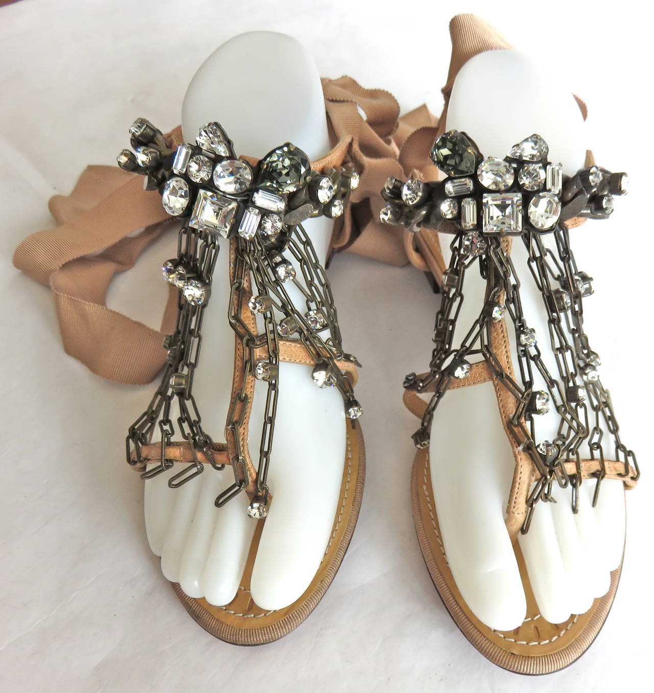 EDITOR'S NOTES:

New LANVIN PARIS Leather T-strap sandals with peach, grosgrain ribbon ties

Thick, dark brass metal chain with large sized rhinestone embellishments at main, top strap.

Smaller draped chain links at bottom strap with loose,