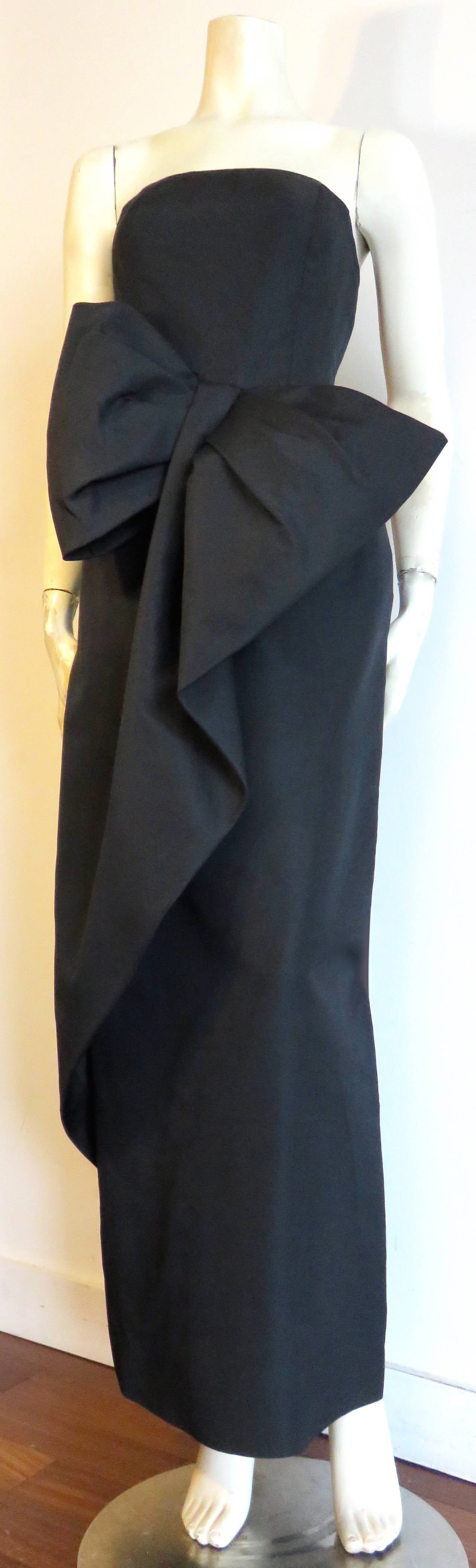 Worn once, early 1970's, MIGNON, 'Gilda' inspired evening dress.

This gorgeous dress is made of black taffeta, and features an incredible, cascading, draped bow detail at the front waist.

Boned, princess seam bodice with center-back zipper