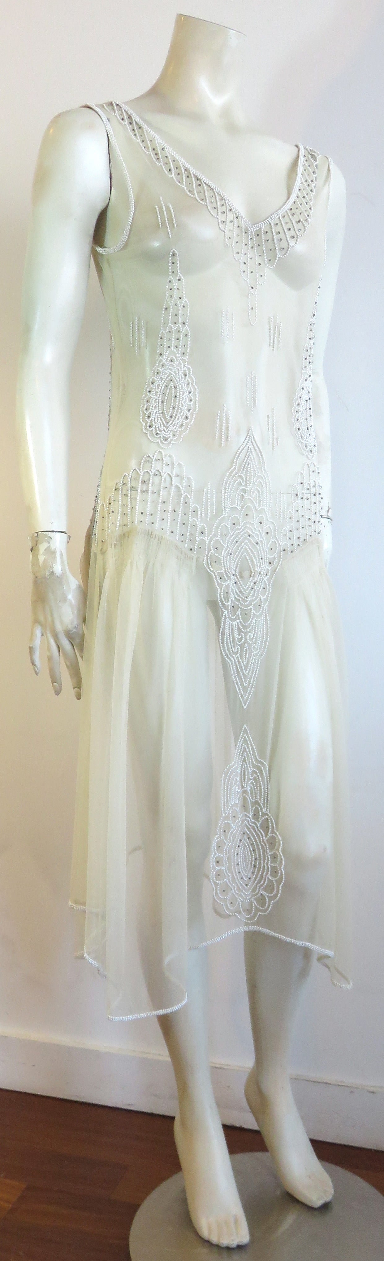 Excellent condition, 1920's-inspired beaded sheer dress from the 1970's.

This gorgeous, top layer, see-through dress is made of sheer, pale beige mesh with mini, glass, and faux-pearl beaded artworks.  

The dress is completely see-through, and