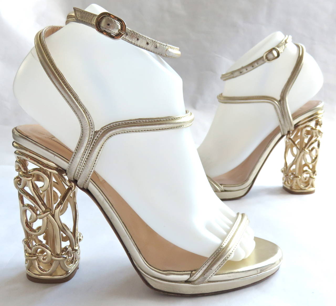 VALENTINO Metallic gold leather & metal cage heels.

Metallic gold leather straps with adjustable metal buckle at ankle.

Polished-gold, finished metal cage-style heels with cursive, spiral metal work.

The shoes are former runway/showroom