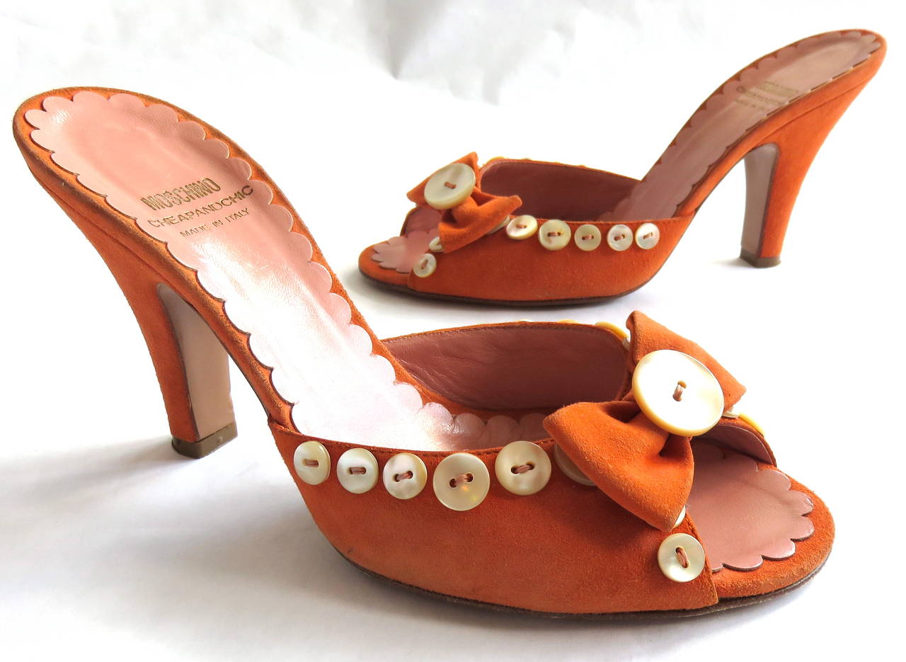 Good condition, 1990's MOSCHINO Button detail suede heels shoes with original box, and dust bag.

Tangerine suede skin shell with pearl button detailing, and bow-tie front.

Open-toe front design with salmon pink, scalloped edge leather