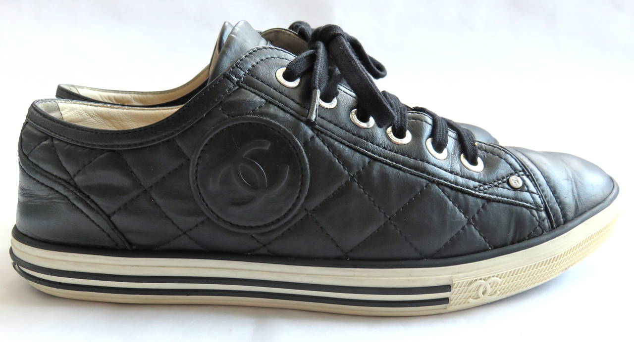 CHANEL PARIS Black quilted logo tennis shoes.

Diamond quilted design with large 'CC' logo, embossed leather circle patches at outer sides.

Soft, lambskin leather front and back panels with coated canvas sides.

Soft leather insoles.

Made