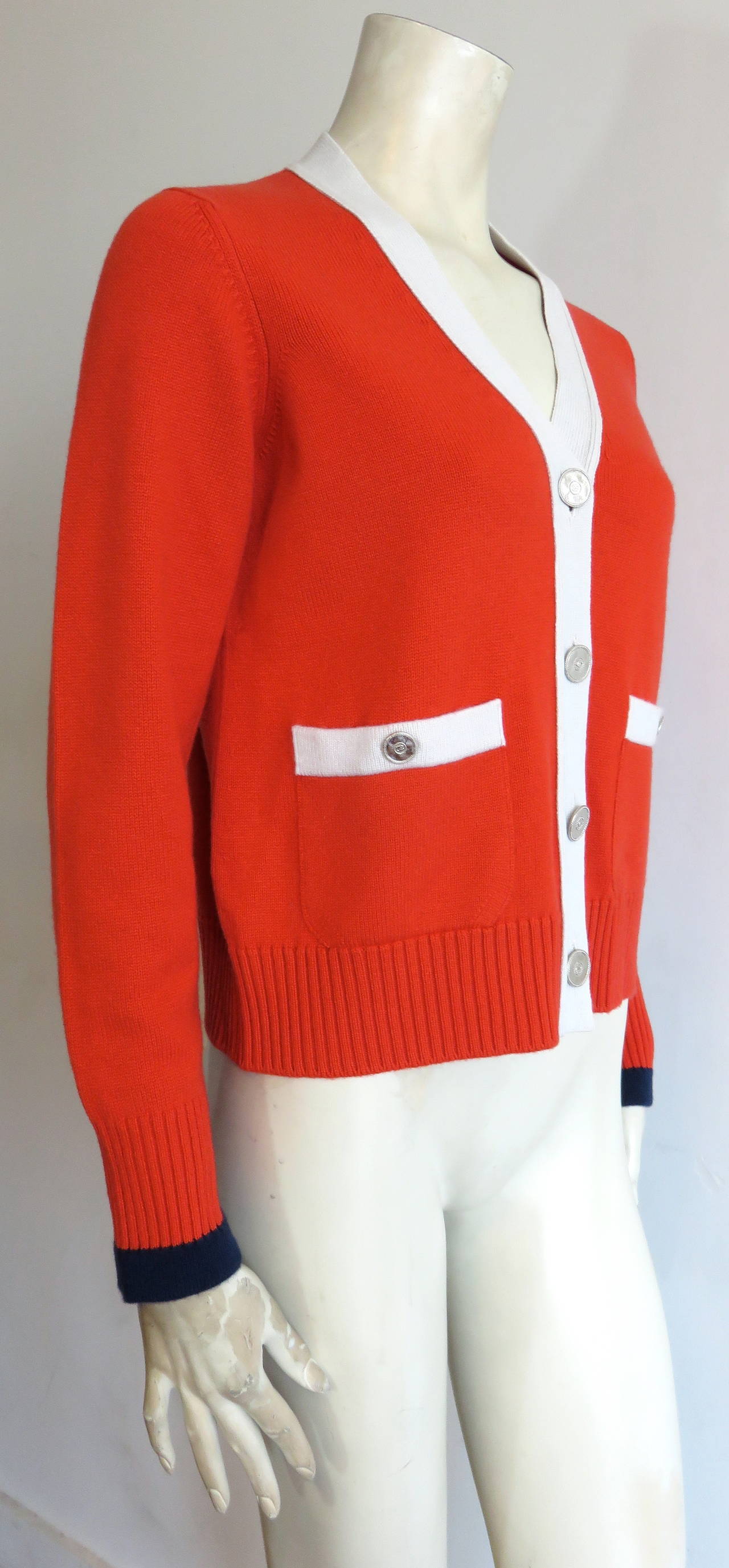 Recent, CHANEL PARIS, pure cashmere cardigan jacket with metal logo buttons.

In excellent condition.

Poppy red/orange ground with off-white placket, and pocket edges.  Navy tipping edge at sleeve edges.

Logo engraved, metal buttons with