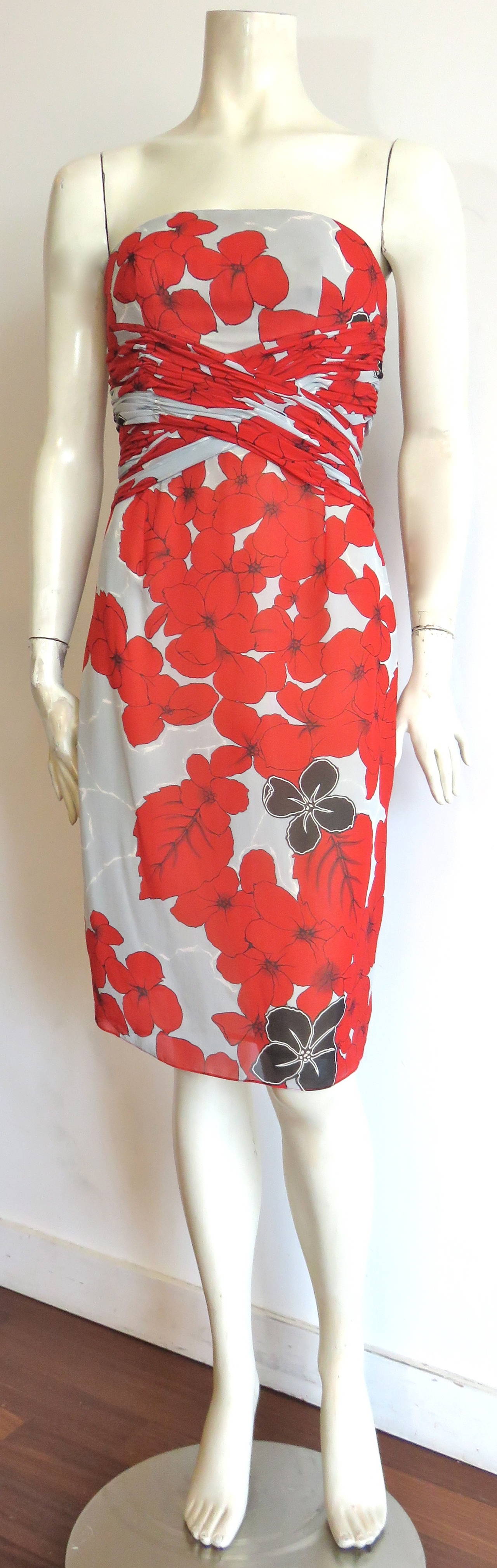 Worn once, CAROLINA HERRERA Silk crepe, floral cocktail dress.

Red and black floral print atop whisper gray/white marble ground.

Flattering, criss-cross, ruché construction at the front waist with attached, long sash tie at the
